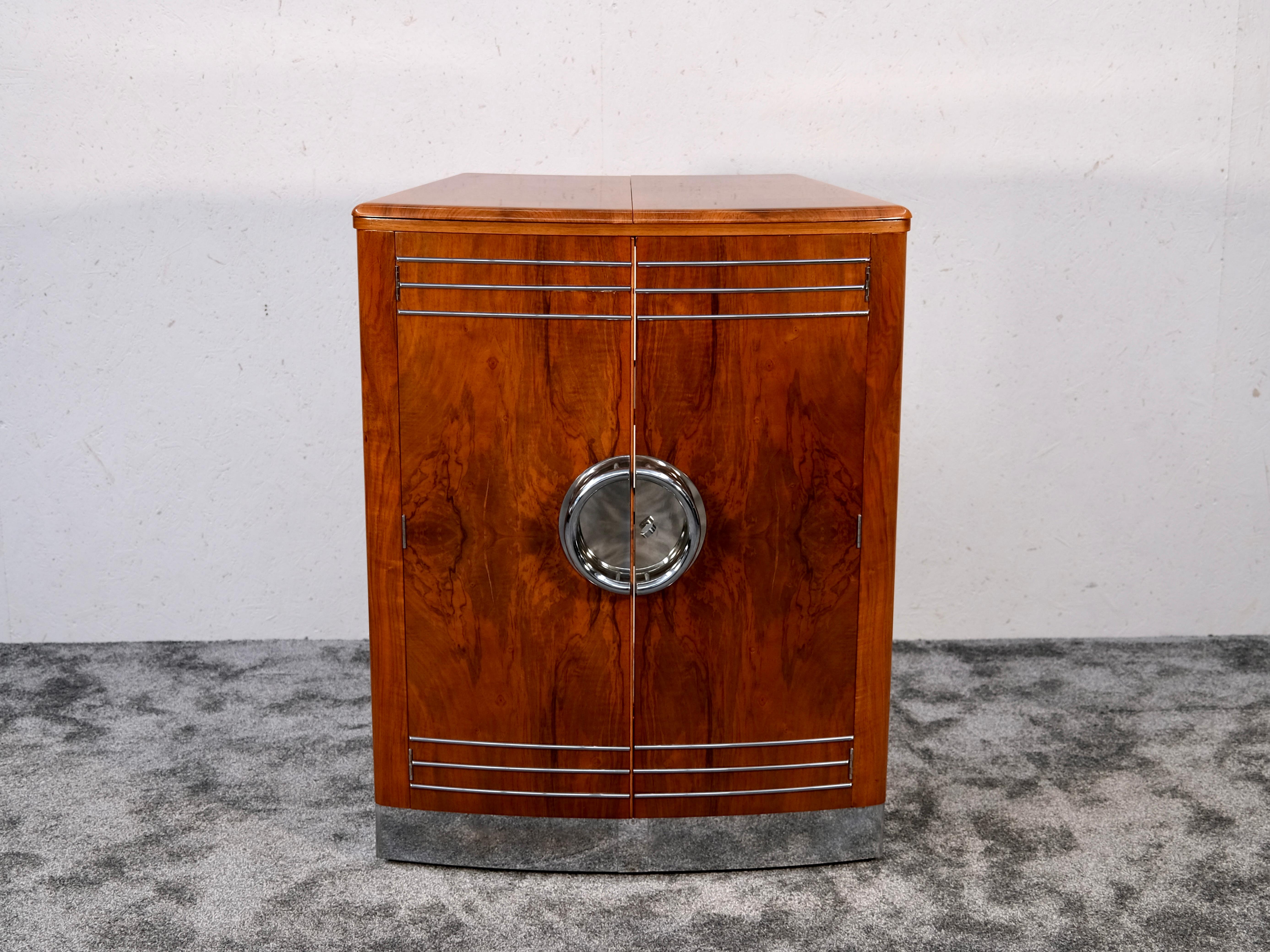 This 1930s English Art Deco Bar Cabinet is a folding bar counter, seamlessly blending vintage elegance with modern functionality. Designed to transform from a compact storage unit into a graceful, curved bar, this piece is ideal for sophisticated