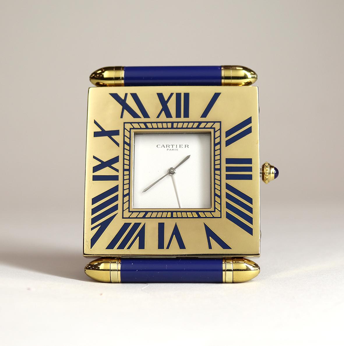 A beautiful ‘as new’ Cartier alarm clock in a gilded folding case with a signed cartier quartz movement and distinctive sapphire cabochon set crown. The foot tolds over and it hinged at the base to cover the dial.

The roman numerals displayed