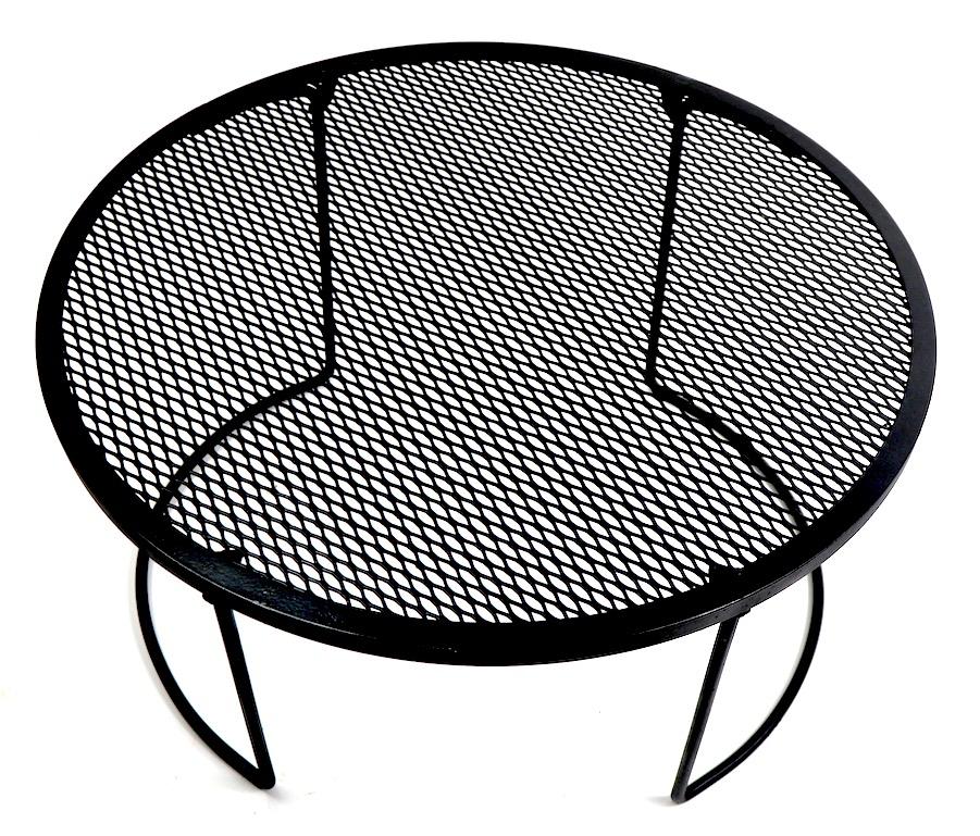 Round metal table with mesh top and wrought iron legs. This table has collapsable legs and folds up making moving and storage easy. Modernist design, table attributed to Woodard. Originally designed for outdoor use, also suitable for indoor