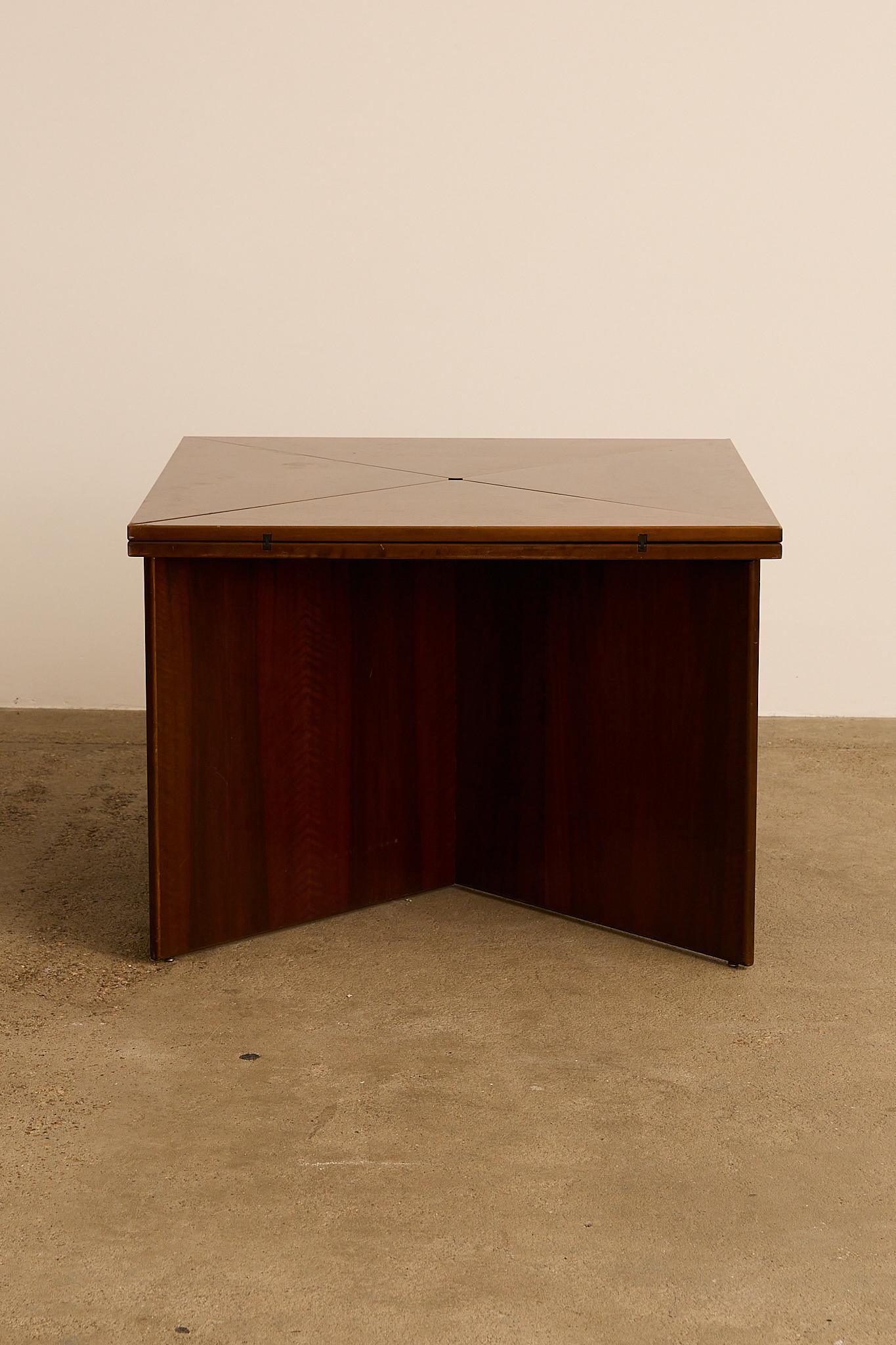 Exceptional table designed by Vittorio Introini for Sormani in the 1970s. Made entirely of rich dark wood, it features an X-shaped base formed by two interlocking panels. The square top expands as each corner unfolds, doubling its size and revealing