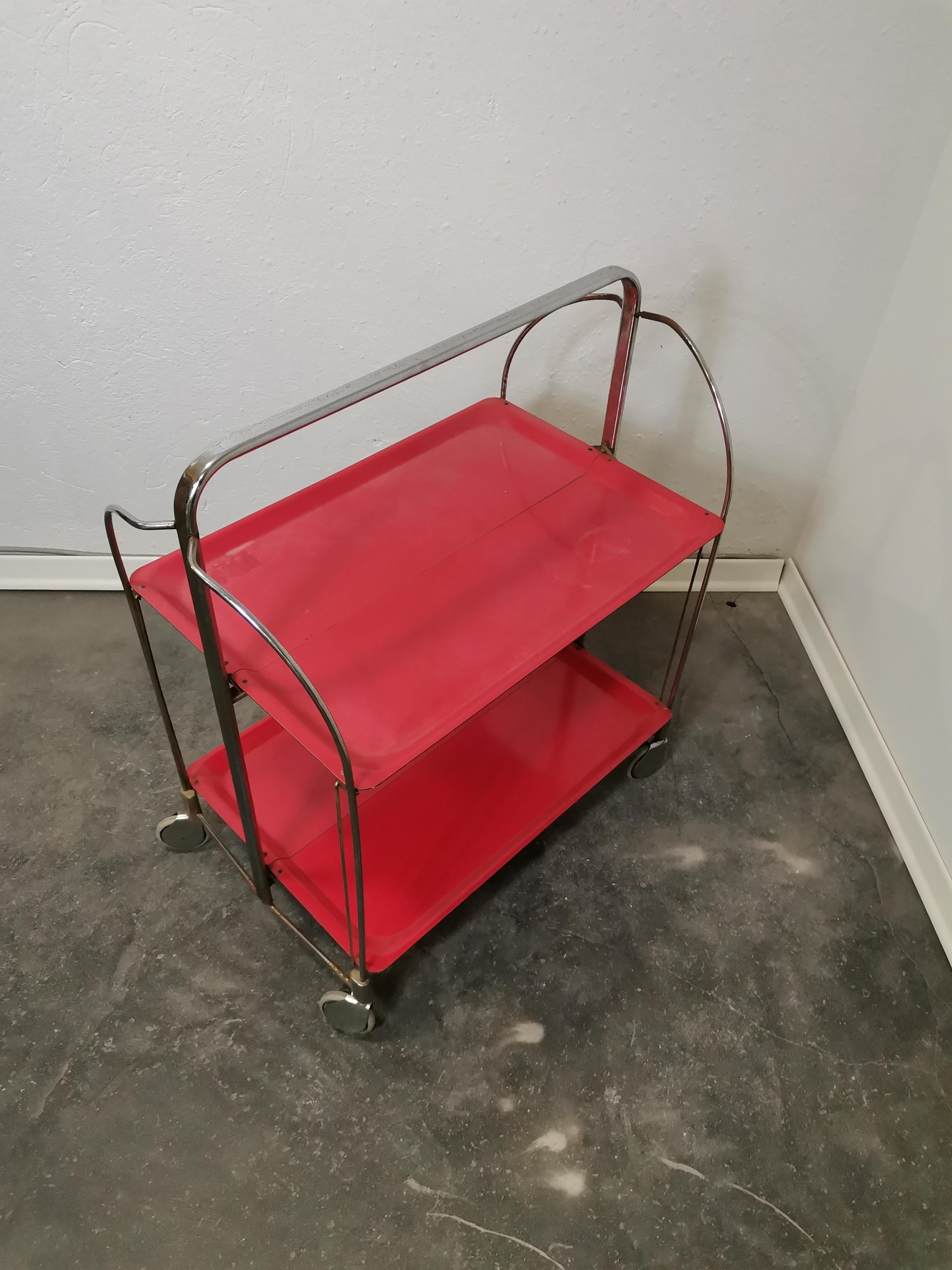 Beautiful trolleys made in Germany in the 1960s' by Gerlinol in black, red and white colour. 1 of 3 - price is for one.

It can be folded and stored.
Chromed side bars and a top handle with two veneer covers.

Good vintage condition with some signs