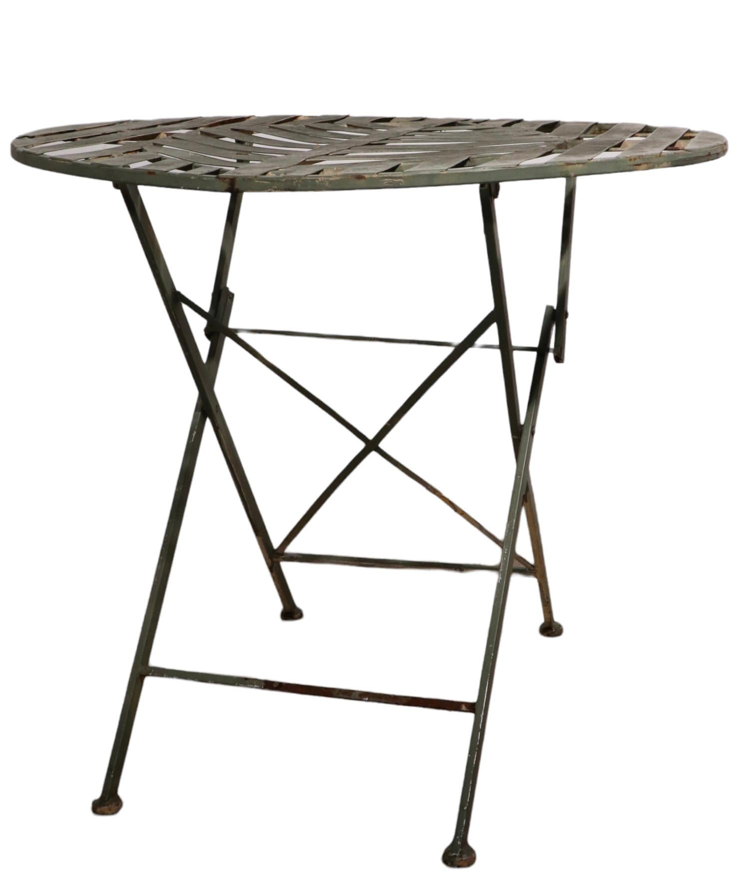Chic folding cafe dining, garden, patio table constructed of metal strips and square stock. The table features a stylized leaf top, it folds up for easy transport and storage. Perfect diminutive scale, sophisticated design, functional, clean and