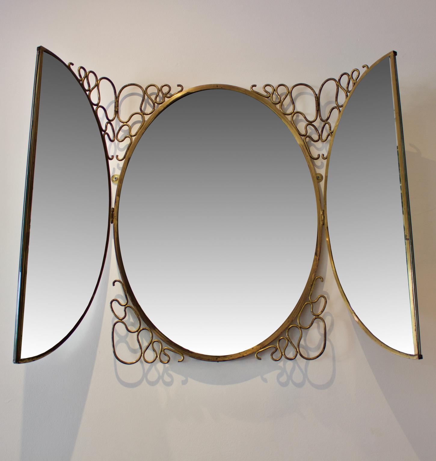 A decorative folding mirror, Italy, 1950s. In the style of Gio Ponti or Borsani Varedo.

The oval mirror is made up of three sections with two outer leaves opening to reveal a central oval mirror. The outer leaves have mirrors on both sides, and