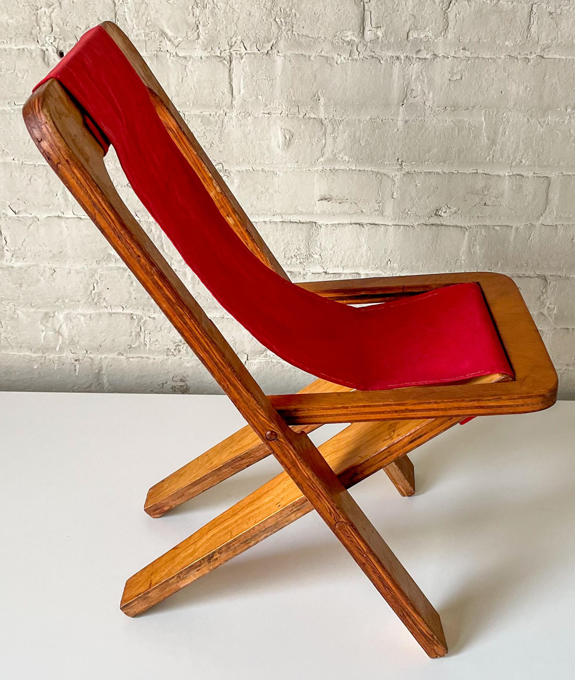 Folding child’s chair composed of three pieces of cut plywood, a canvas sling, and steel pins. The frame pivots open and closed via the pins and a groove cut into the plywood seat. American, circa 1950, in an organic design idiom in the manner of