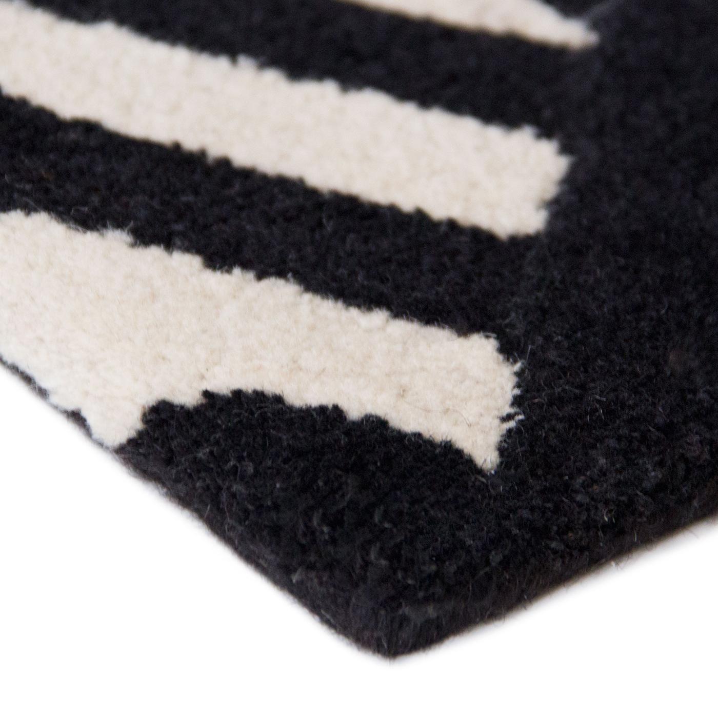 Designed by Serena Confalonieri, this captivating rug is a mesmerizing addition to a modern interior. It is crafted by master artisans using exclusively virgin wool sourced in New Zealand and boasts a geometric motif of juxtaposing black and white