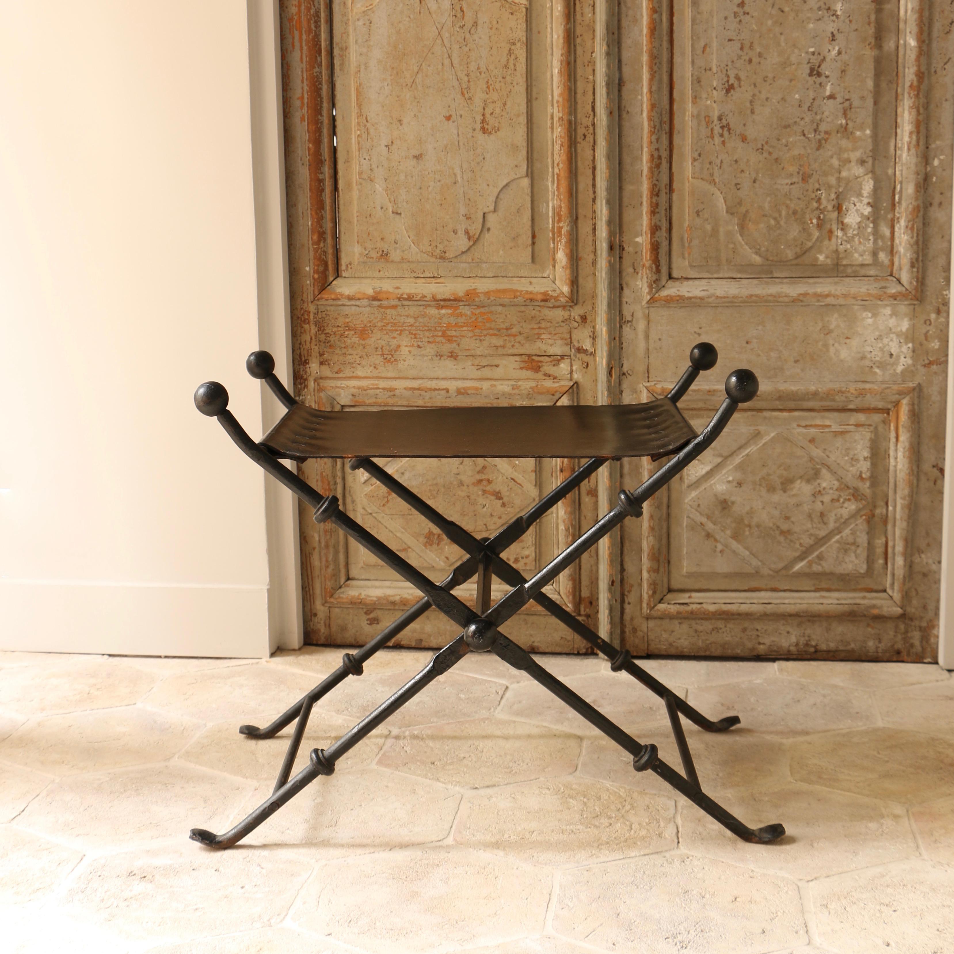 This folding stool, typical of the 1940s, is composed of a bronze structure, and its original studded black leather seat. We like the simple lines of this stool which constitutes a very graphic whole, located halfway between modernity and charm of