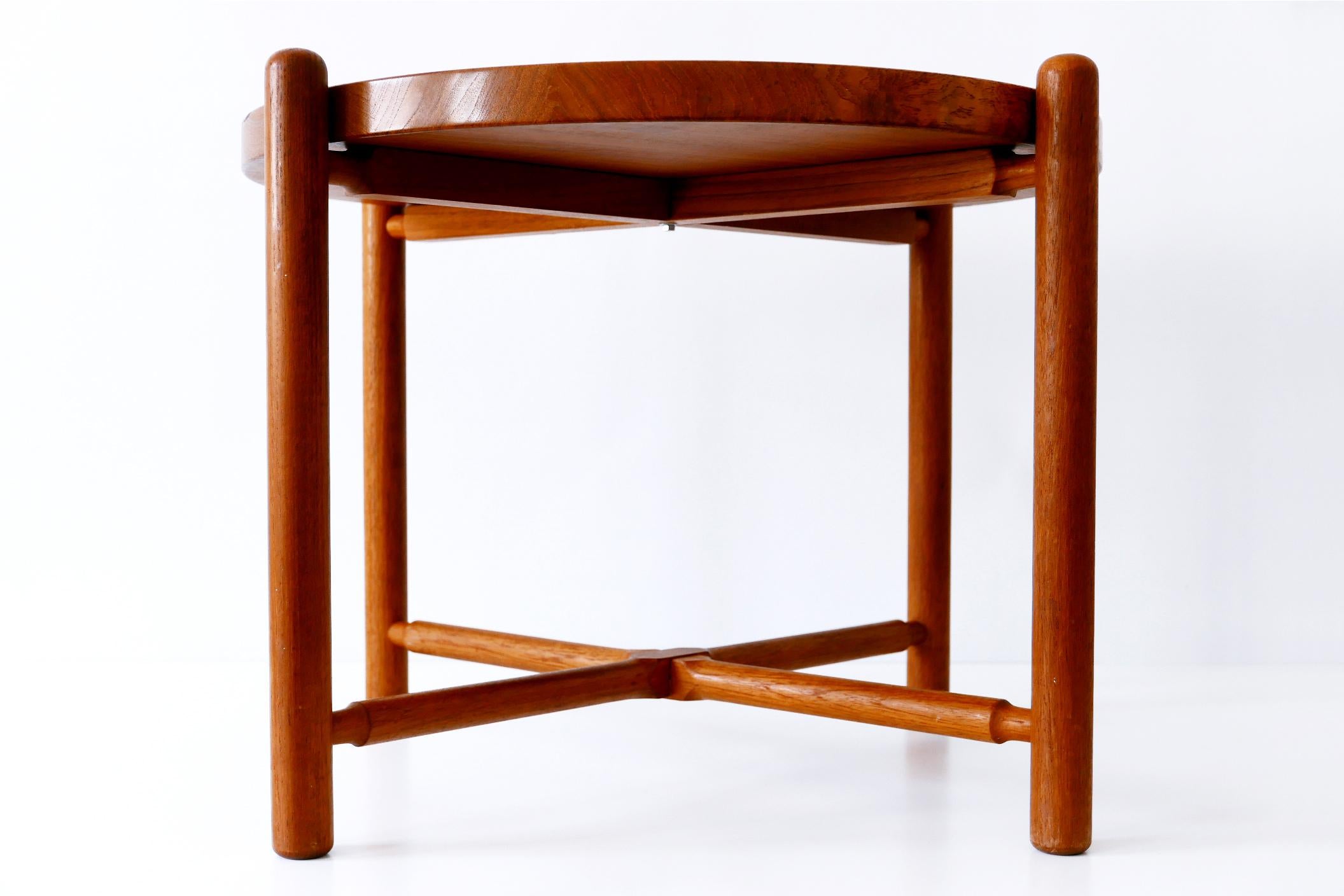 Rare Mid-Century Modern folding coffee table with massiv teak tray and base. The table top with a delicate lip sits loose on the base which is foldable. 

At first sight it seems to be similar to the folding table AT-35 of Hans J. Wegner. But
