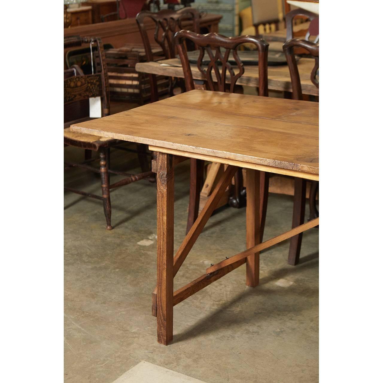 This striking piece is a wallpaper table with centre supports that unhook from the table top to allow the legs to fold inward. The piece has simple striking lines and would work great as a dining or work table.
  