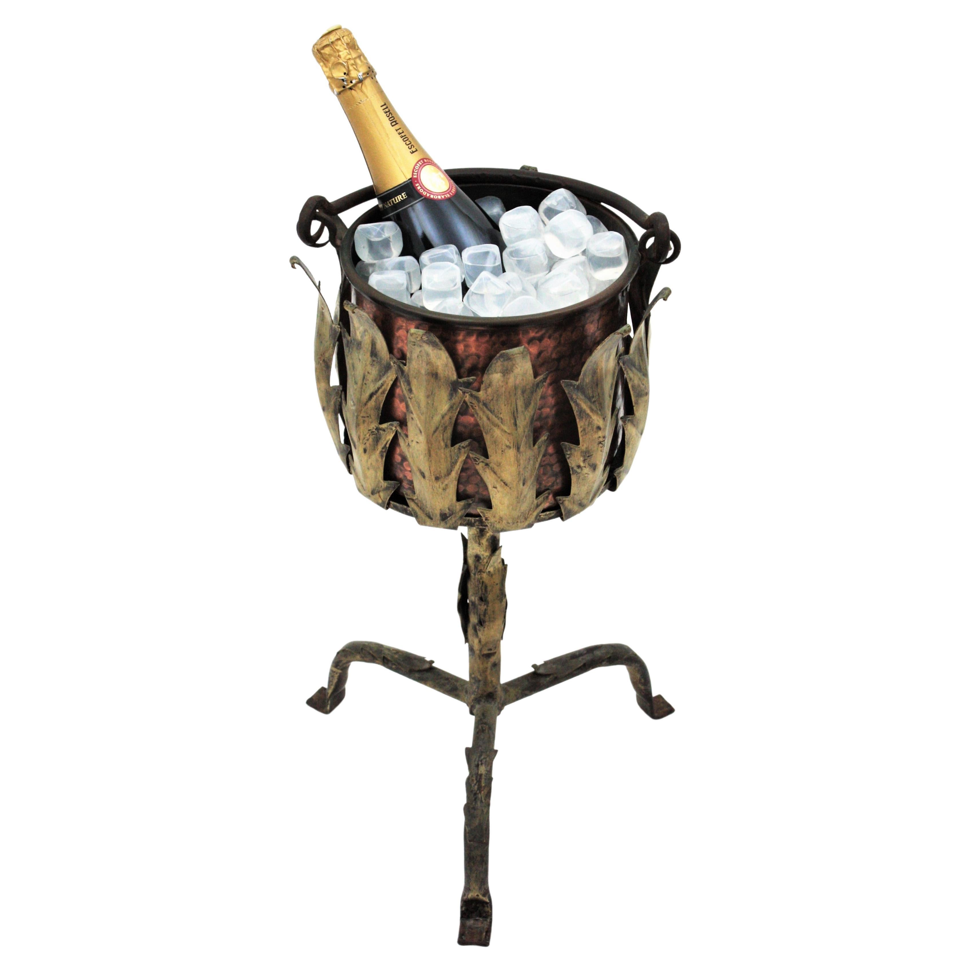 Foliage hand forged iron tripod stand with hand-hammered copper ice bucket, Spain, 1940s.
This pedestal champagne or wine serving stand is all made by hand. The handwrought leafed iron stand stands up on a tripod base with foliage decorative