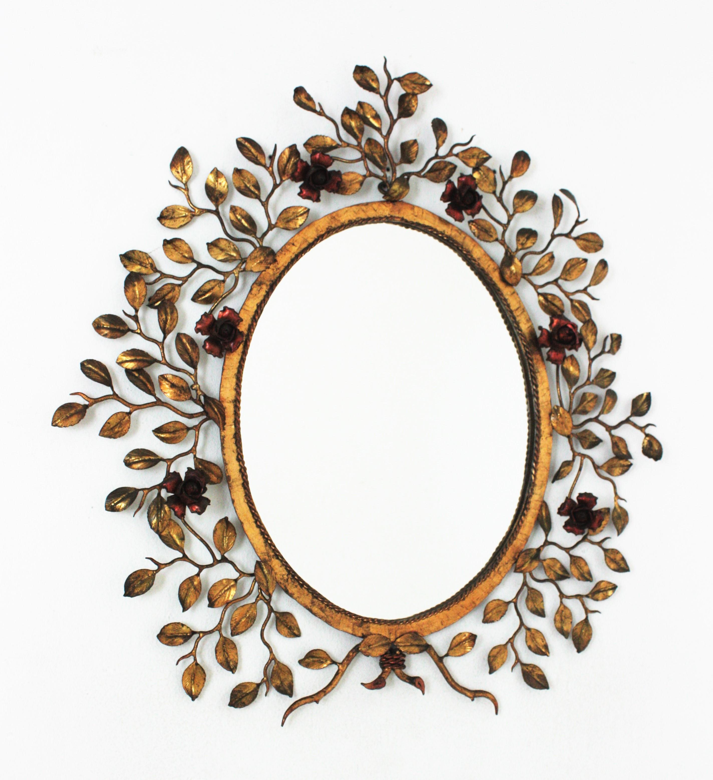 Outstanding foliage Floral Oval Mirror in Gilt Hand Forged Iron, Spain, 1950s.
Hand wrought iron oval sunburst wall mirror with foliage frame, red floral accents and gold leaf gilding.
The frame features and intrincate of branches and leaves with