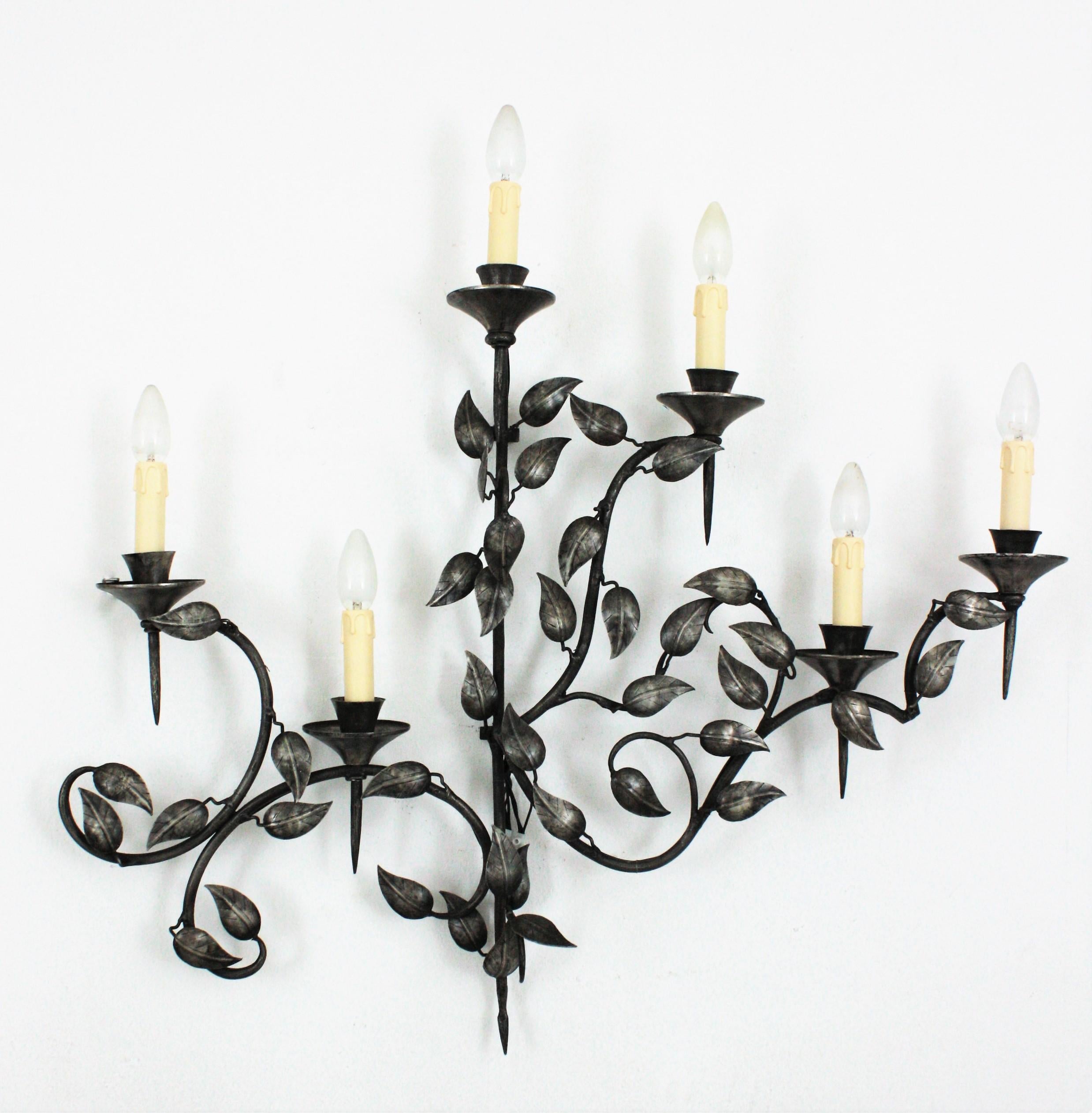 Leaves wall sconce with 6 torch shaped lights patinated in silver and foliage design. Spain, 1950s.
This outstanding wall light features an intrincate of leaves with branches holding 6 torch shaped bulb candle shaped holders.
Silver leaf and