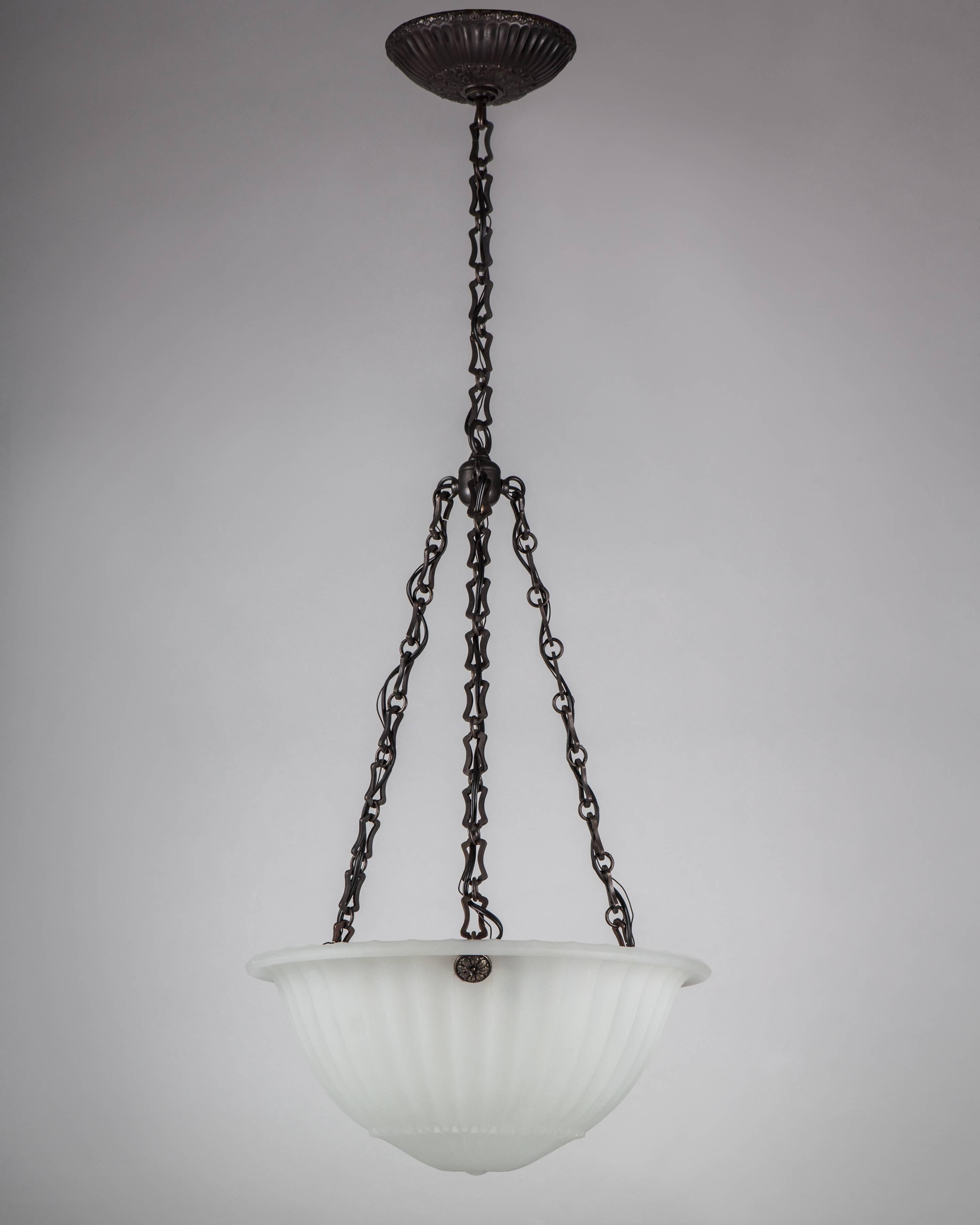 AHL4131
An inverted dome chandelier with a cast opaline glass body having a foliate rosette center and fluting above, suspended on darkened brass fittings. Due to the antique nature of this fixture, there may be some nicks or imperfections in the