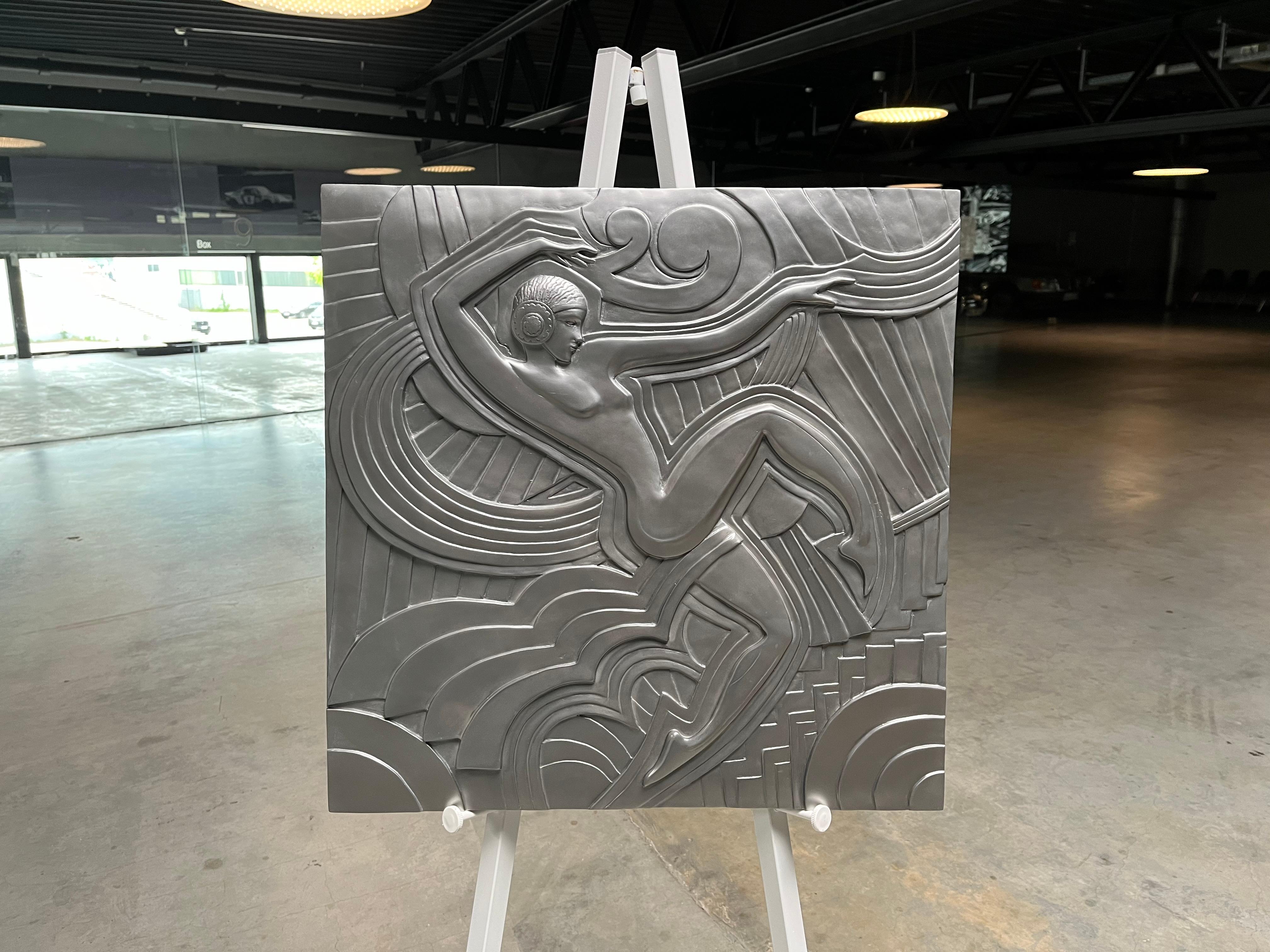 Silver colored wall plaque made after the model that decorates the facade of the revue theater “Folies Bergère” in Paris. This meter-high relief dates from 1926, by the French architect and designer “Maurice Picaud”, called “Pico”. The depicted