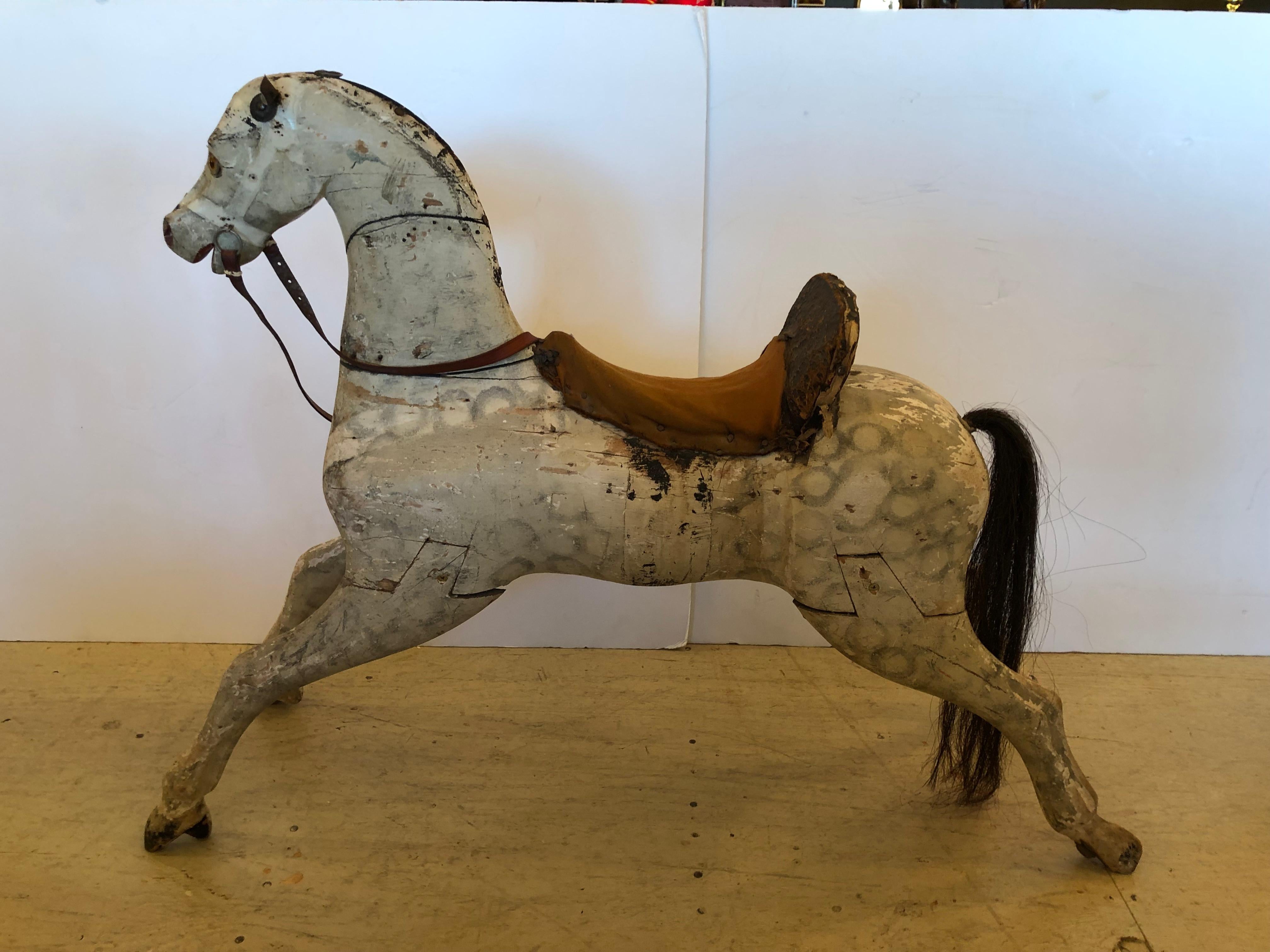 19th century wooden rocking horse with rocking base removed. Made of wood, horse has a worn leather saddle and leather reins. Eyes are made of glass and horse hair tail. A wonderful piece of Americana.