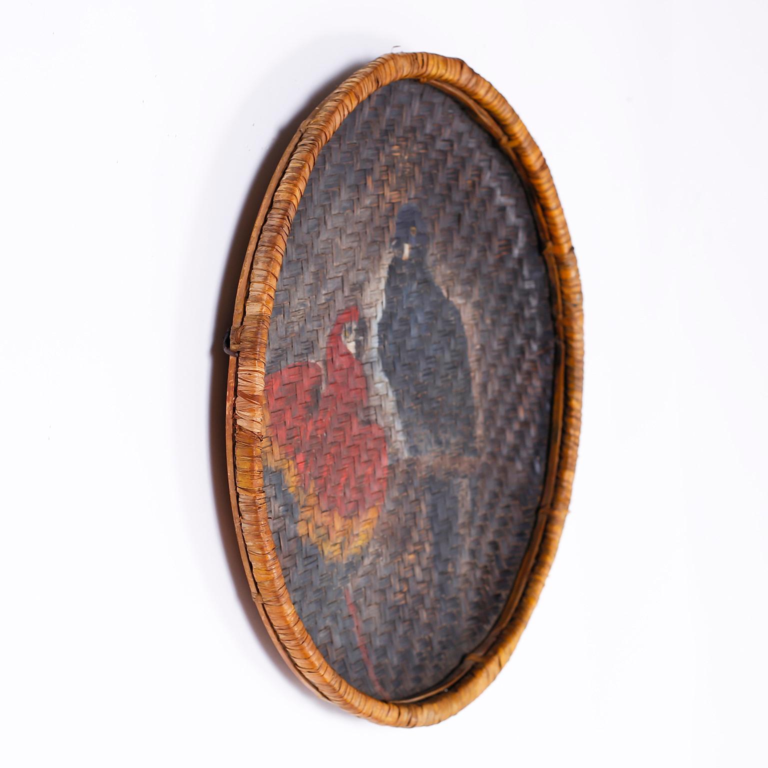 Antique handmade basket now a wall hanging woven in a herringbone pattern with a mysterious painting of two parrots aged to perfection.