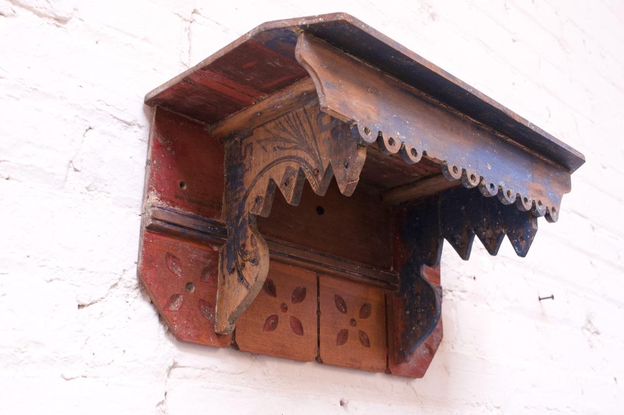 Hand painted and carved small oak shelf (circa 19th Century, USA) with a single surface to accommodate smaller objects. Only one side features a drawn linear design, as shown. Interesting combinations of carved shapes and colors (indigo, brick red,