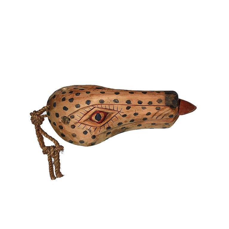 A beautiful one-of-a-kind carved wood wall hanging of a dog. This piece was sourced from Indonesia and is made of light wood. It depicts the face of a dog with black painted spots and red decorative details. At the top, a rope is attached for