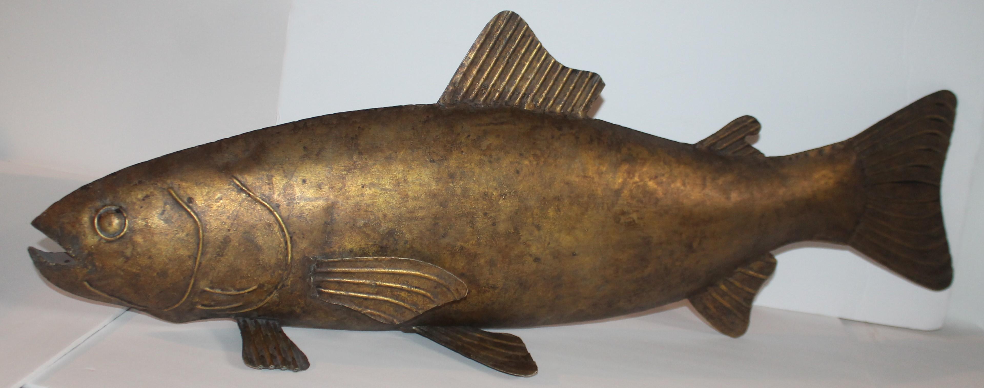 This amazing 20th century handmade Folk Art gilded metal sculpture of a fish is in fine condition. It is unsigned and not sure if it was made to hang in a fish house or grill. Perhaps on a fresh fish market. Great as display on a shelf or cupboard.