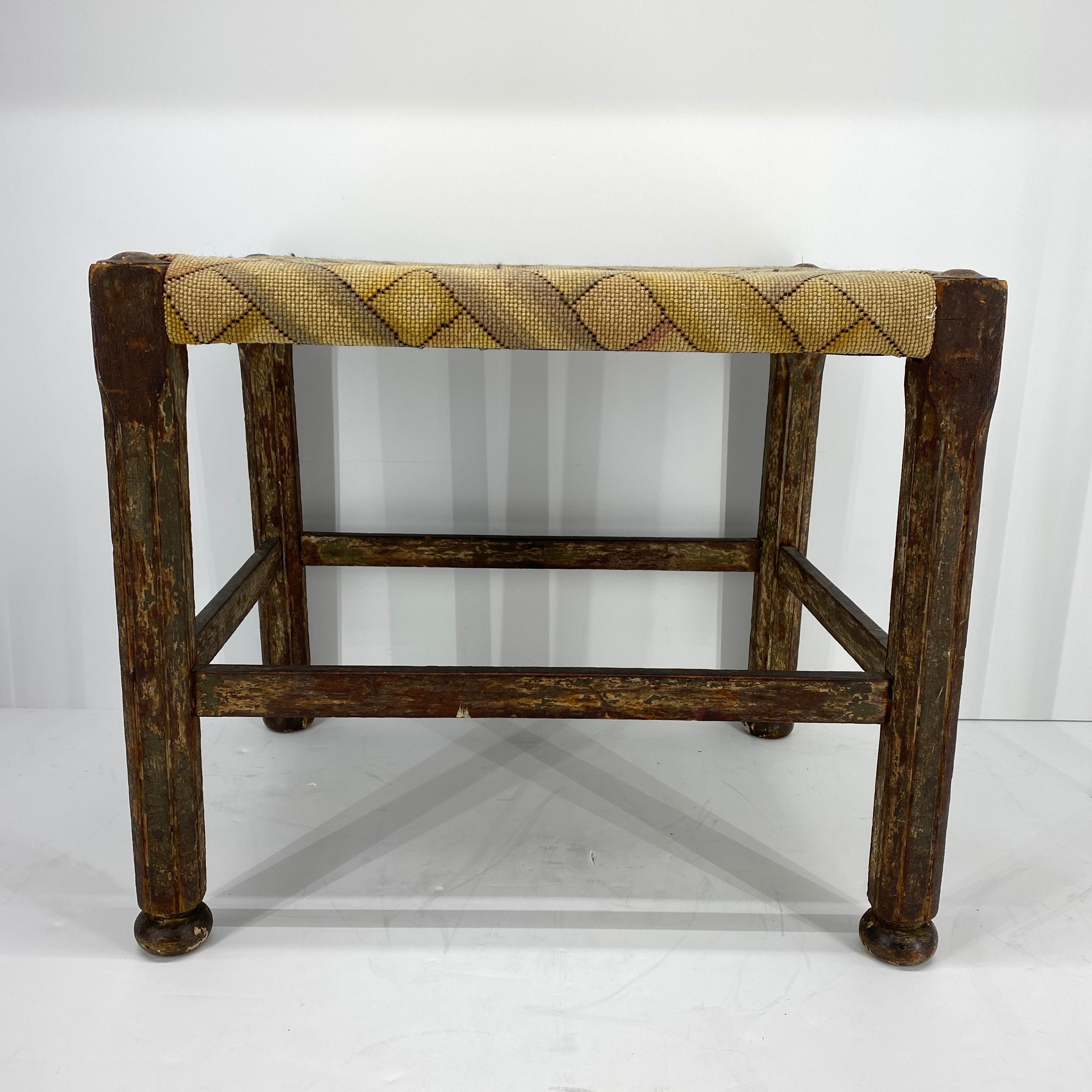 Folk Art mid-19th century footstool. This stool has colorful patterned woven print seat with faceted legs. The stool is sturdy and functional. The footstool has an interesting character; this is a one of kind, whimsical stool that is an excellent