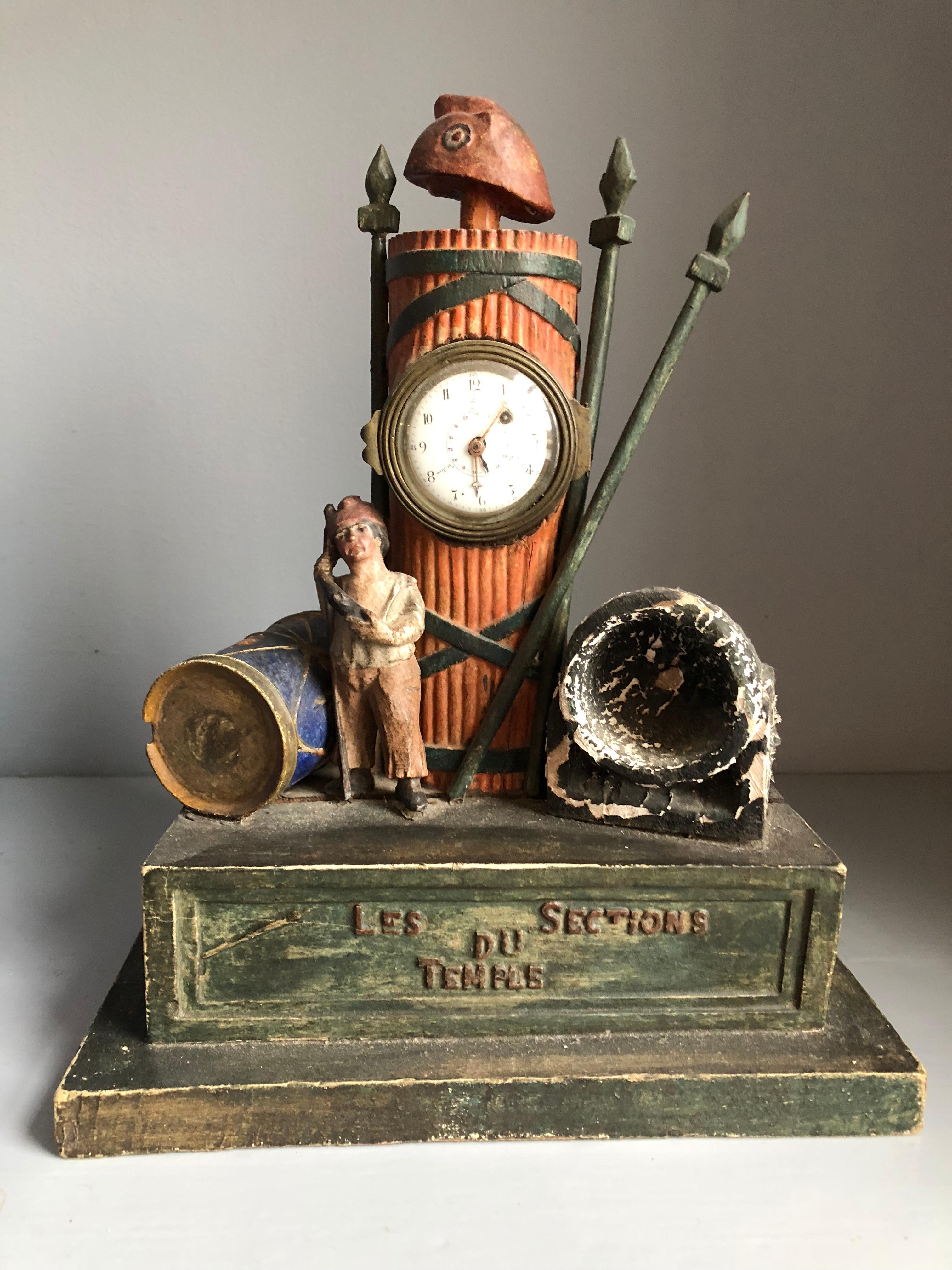 A French folk-art figural mantel clock in carved wood and composite commemorating a fighting unit “Les Sections du Temple” in the French Revolution. The clock depicts a single figure “sans culots” with a walking stick flanked on one side by a drum