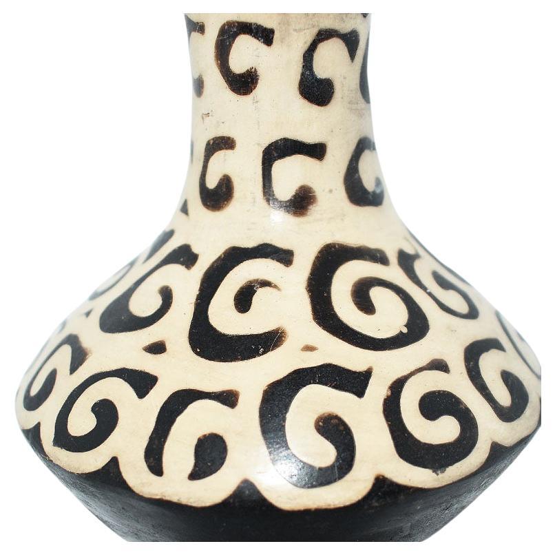 A small round geometric flower vase in black and cream. The body of this piece is wide in form and is decorated with deep brown or black swirl designs on a cream background. The bottom and neck of the vase are in black. This would be a wonderful