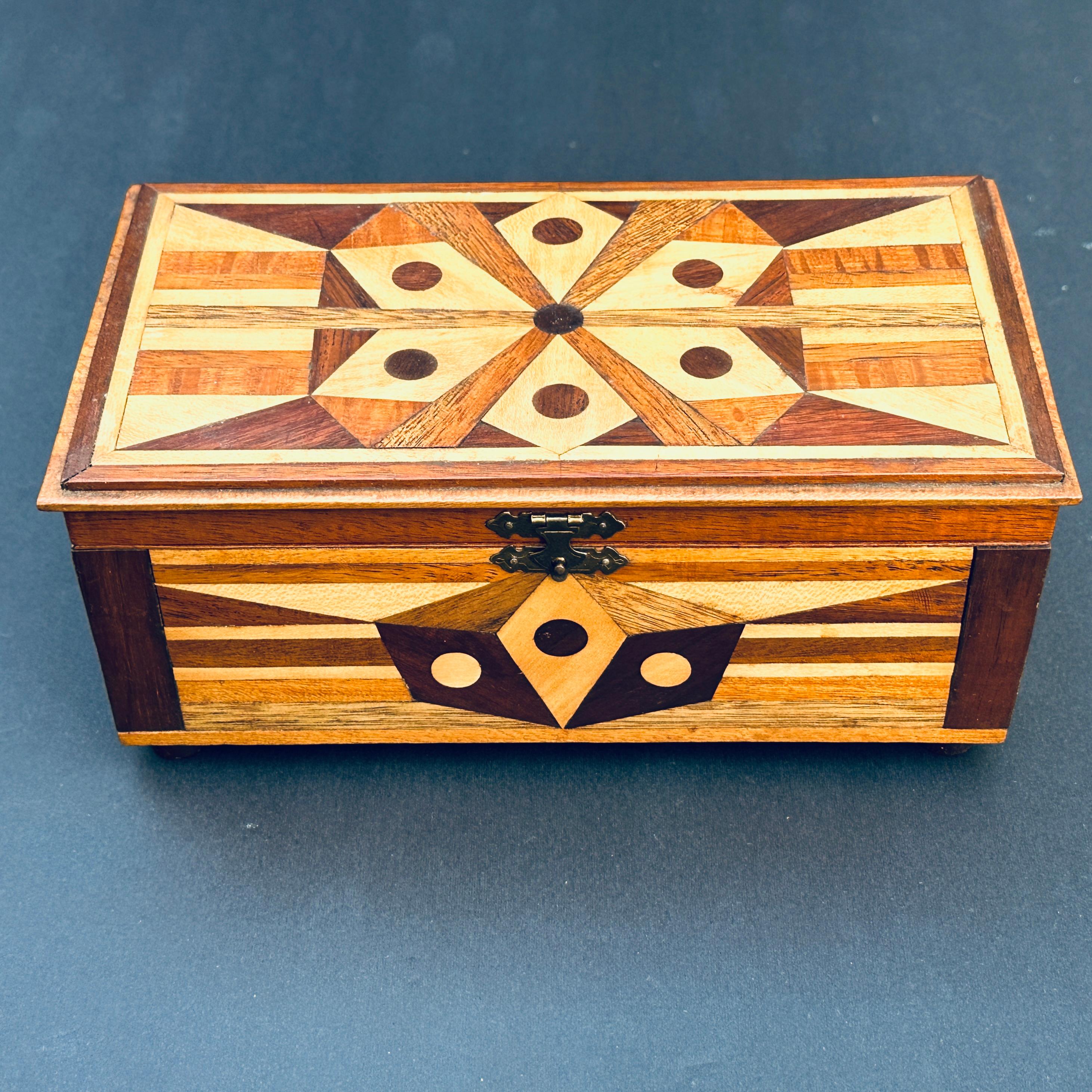Handgefertigte geometrisch eingelegte Holzscharnierbox mit rot emaillierter Innenseite.