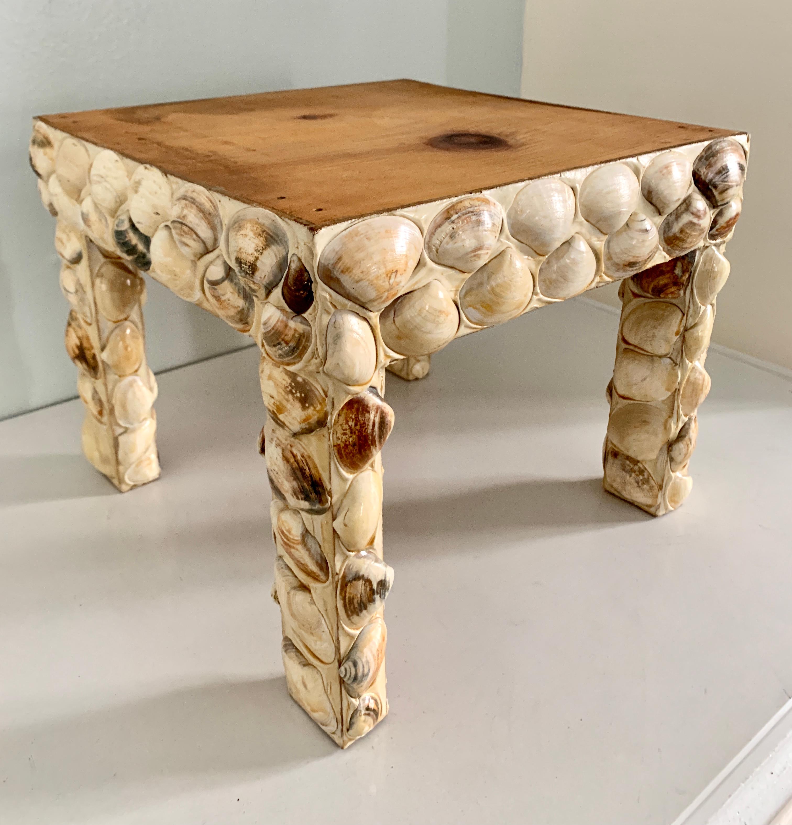 A wonderful table perfectly suited for many rooms or spaces and especially those near the sea side or with an ocean theme. The tables legs are covered entirely with Cockle shells and in very good condition. The top is exposed wood to remain flat for