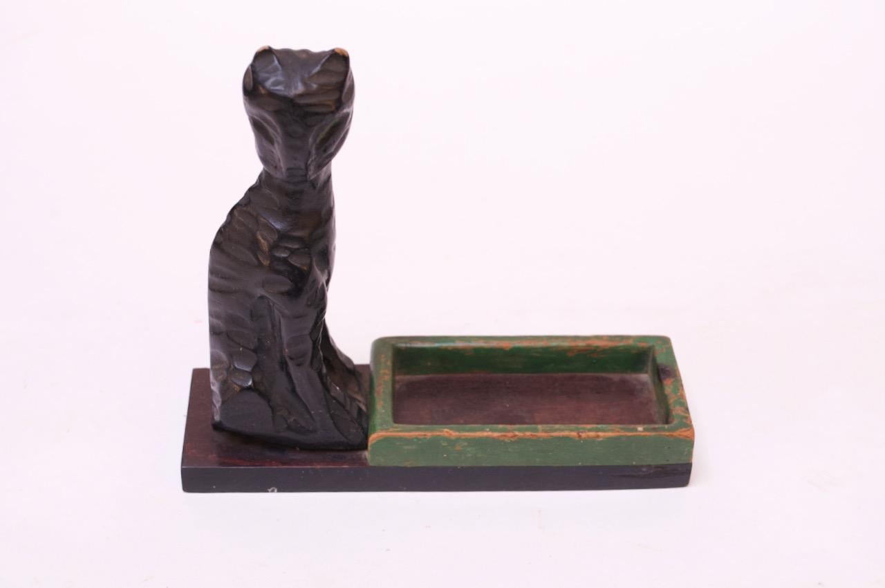 Wooden ebonized cat with dish sculpture mounted to a mahogany plinth. Dish can accommodate keys or smaller objects.
Patina / light wear present (paint loss to the tips of ears / edges of green dish).
Small size: H 5.75
