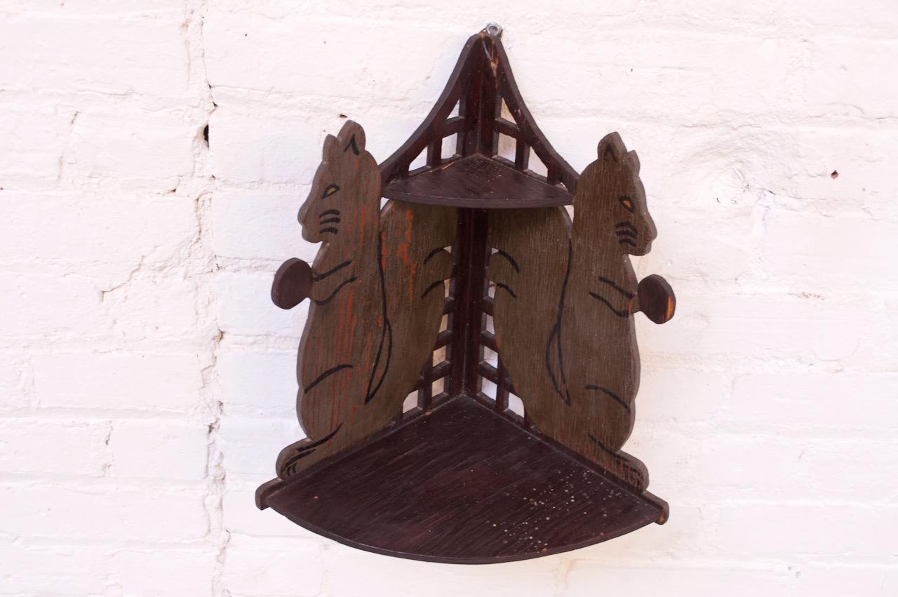 Charming Folk Art oak corner shelf with dual carved and hand painted 'squirrel with acorn' decoration (circa early 20th Century, USA). Two-tier: a small triangular top and wider lower surface. Crazing / paint loss consistent with age present.