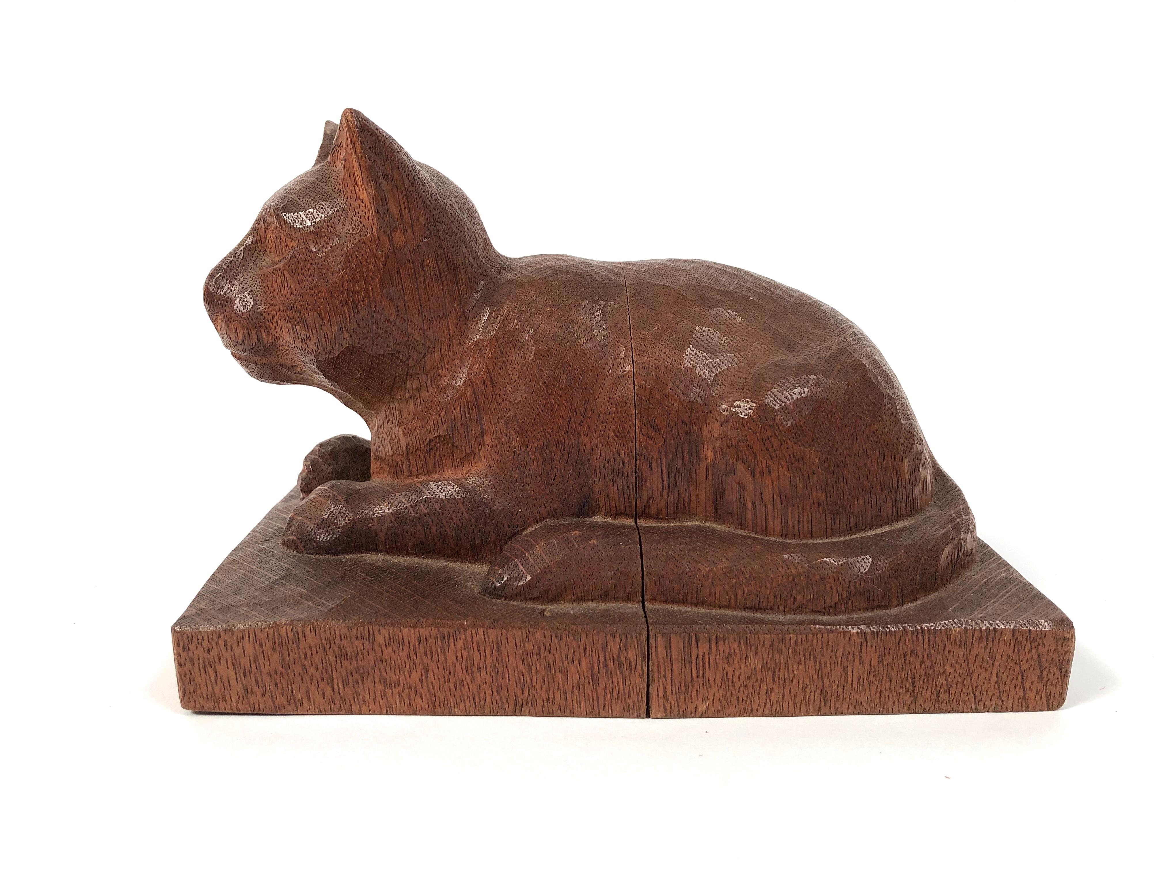 A beautifully hand carved wood folk art sculpture of a cat, in oak, resting, with alert expression, on a rectangular plinth, American, circa 1890-1900.