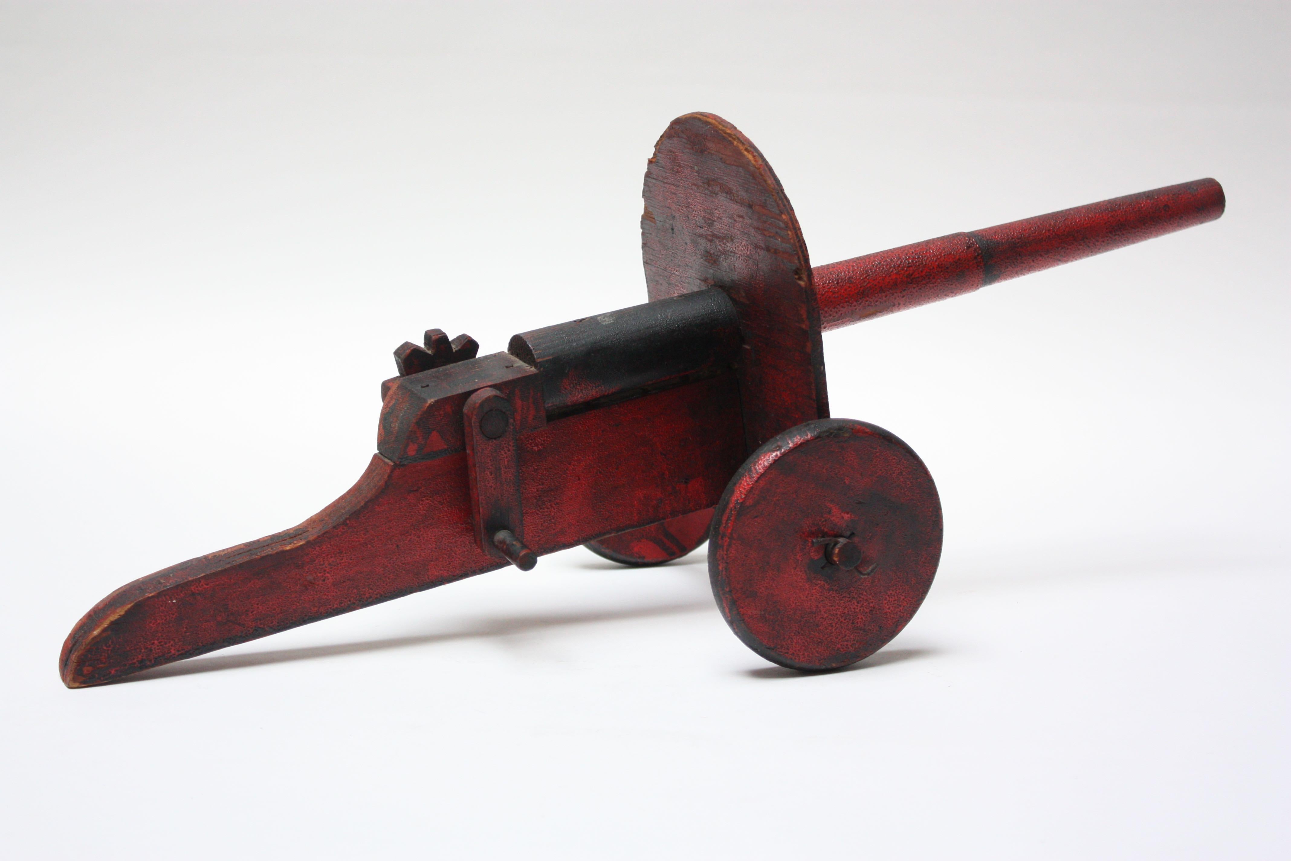 Canon jouet Folk Art en peinture noire et rouge d'origine, vers les années 1930, USA. Perte de peinture très mineure partout et perte de bord sur le bouclier, comme illustré.
 