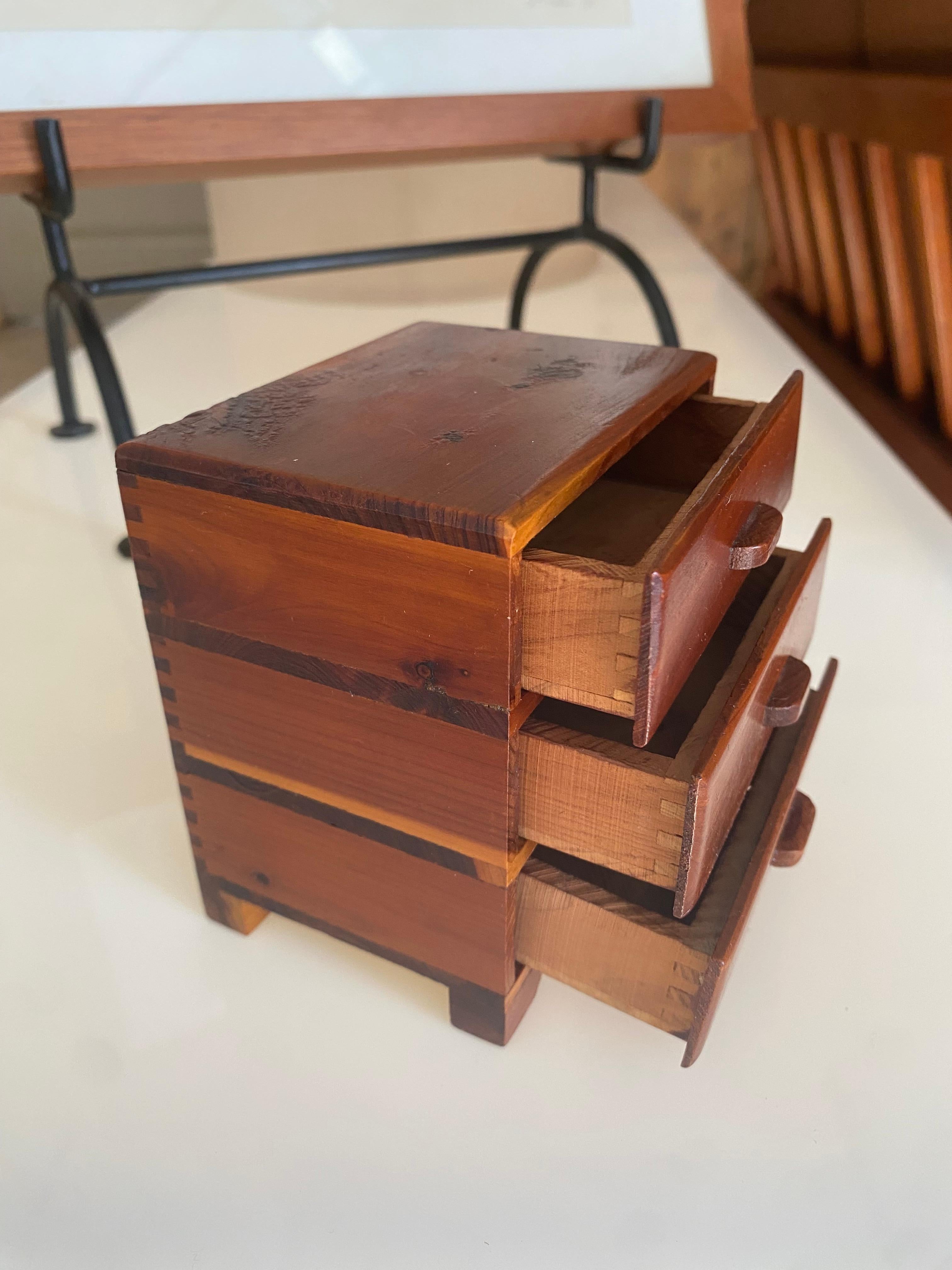 Commode miniature d'art populaire avec trois tiroirs fonctionnels et une menuiserie à queue d'aronde. Cette pièce joyeuse est fabriquée à la main avec un tel soin que même les tiroirs intérieurs sont réalisés avec la même menuiserie que le coffret.
