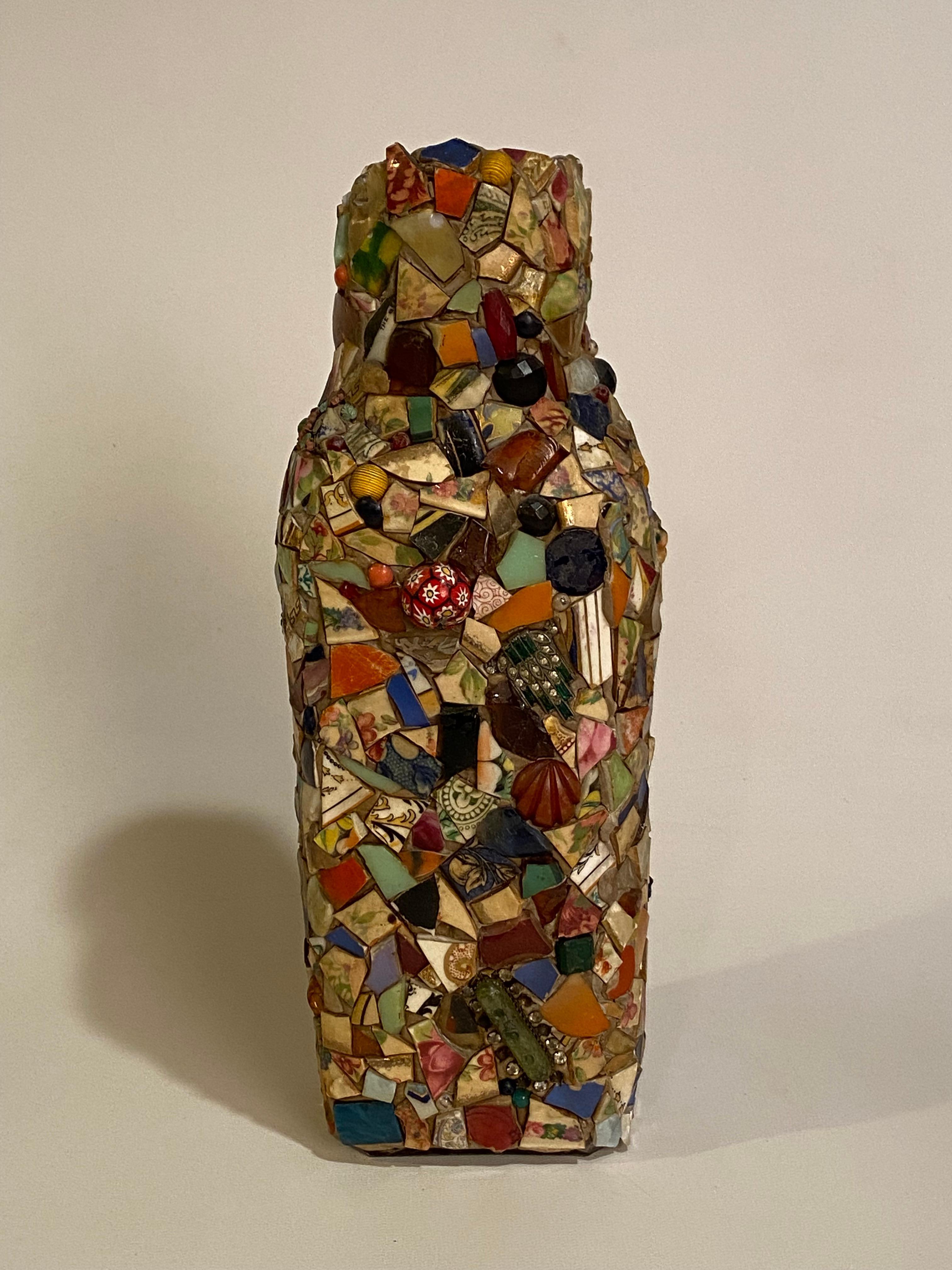A beautiful and complex folk art mosaic bottle. Clear glass milk bottle that is covered in countless fragments, broken porcelain, jewelry, Bakelite, glass, beads, pottery, clay... A wonderfully complex menagerie of vibrant color and texture. A