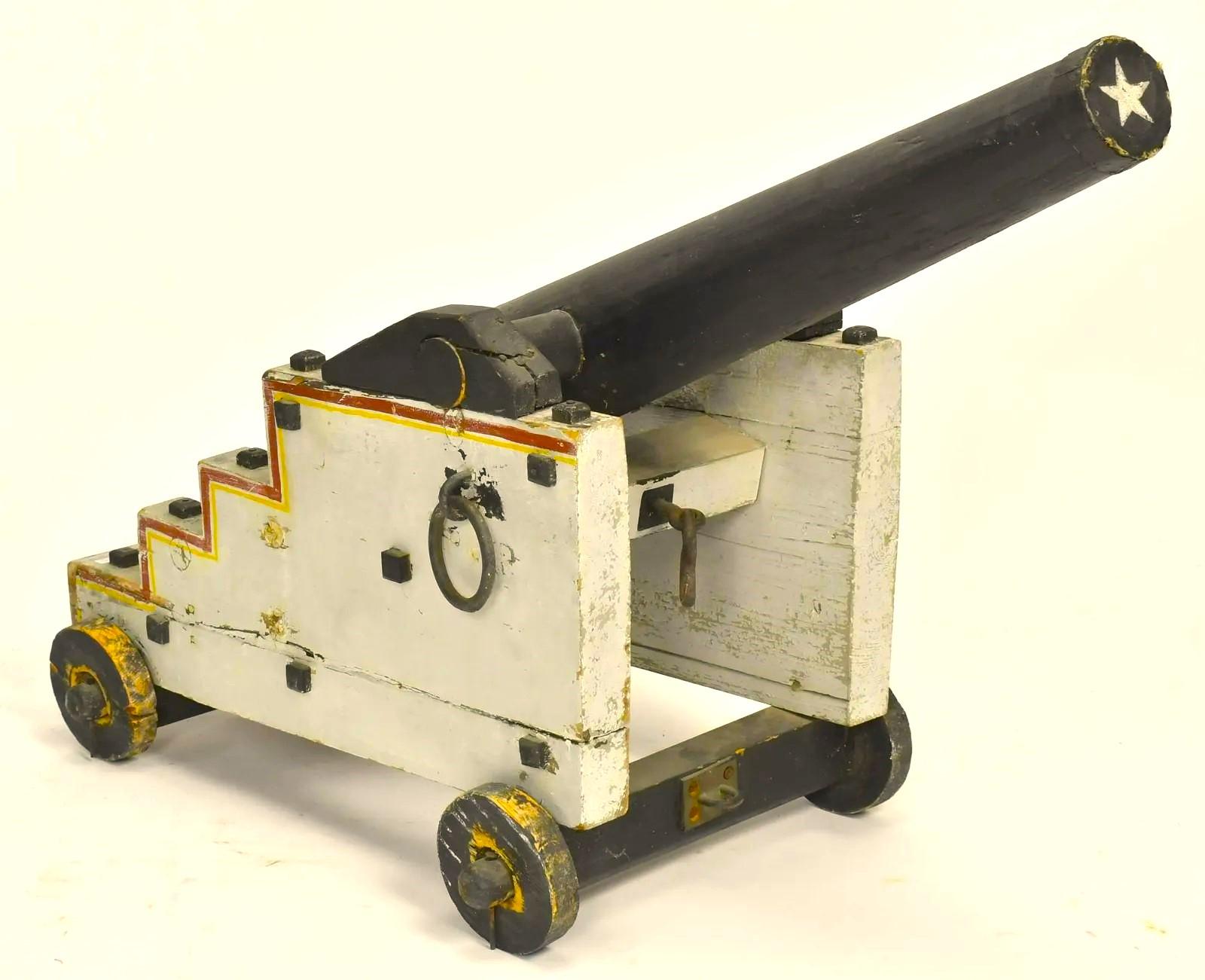 A unique folk-art naval cannon, in carved and painted wood, with rolling wood wheels and other decorative details, circa 1900.