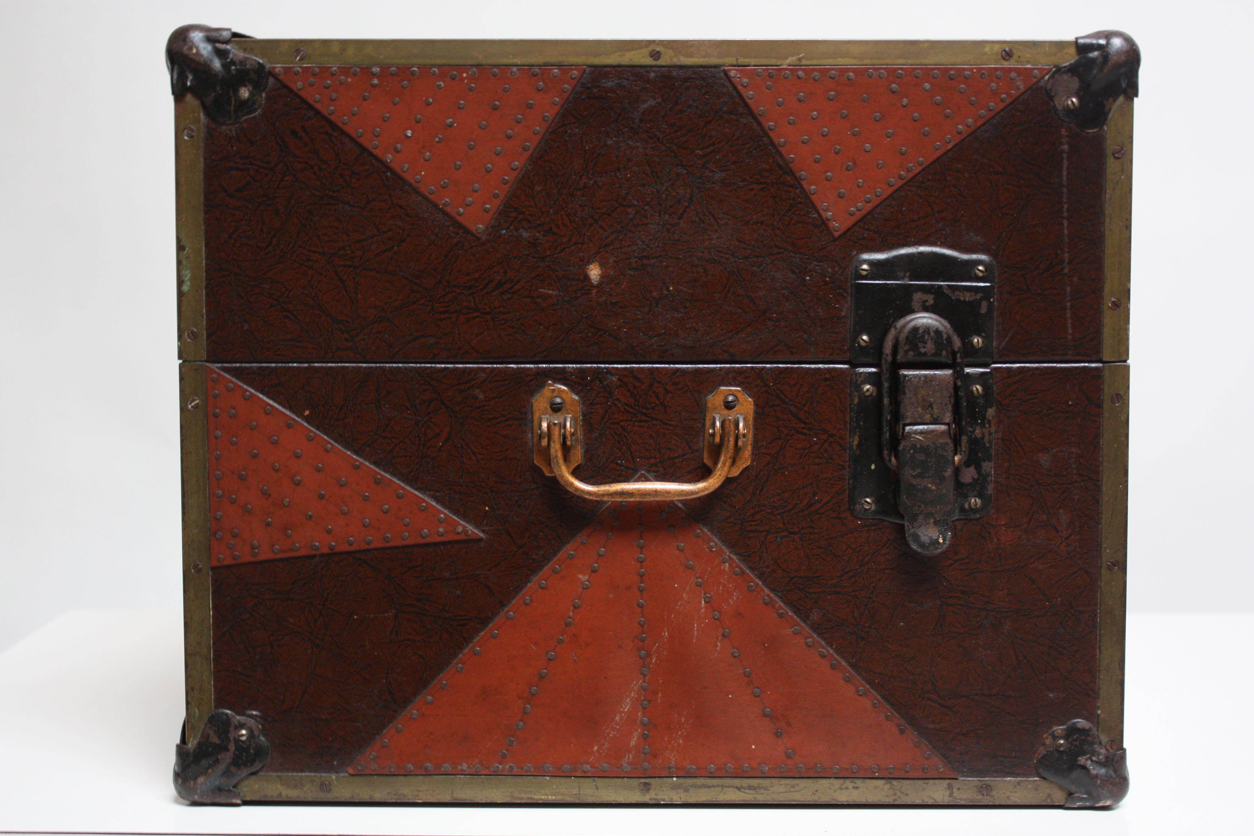 Folk Art metal box with hand-hammered and applied red and black cut-out decoration secured by nailhead trim. All mechanisms are intact, and box opens easily by releasing three latches. Part of the interior lining is missing and one piece is