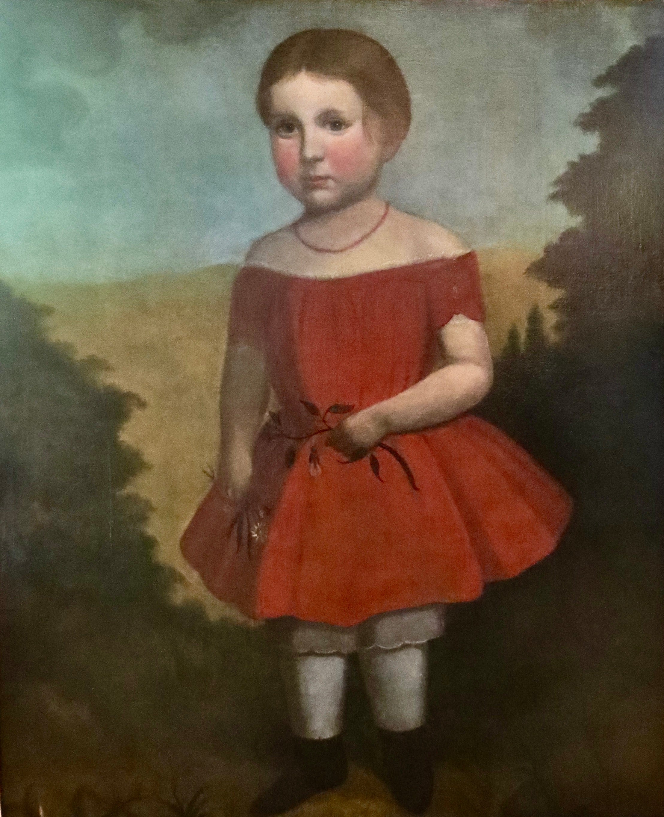 Lovely full length portrait of a young girl in this folk art painting; oil on canvas mounted on board. She is posing wearing an attractive and colorful red dress while holding a floral branch in each hand; a colorful and a fabricated pastoral