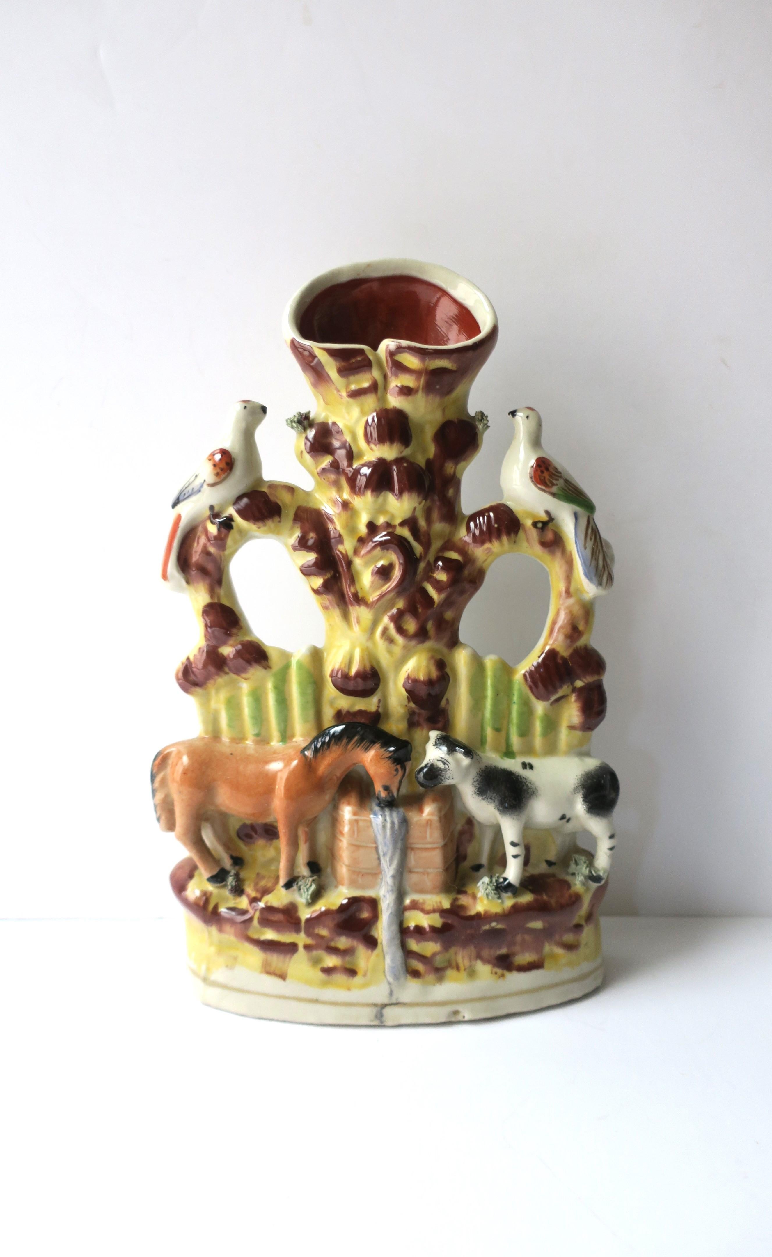 An animal farm scene pottery spill vase, Folk Art design, attributed to Staffordshire, circa early-20th century, England. A beautiful scene of dove birds on perch at top, and horse and cow below drinking from trough. Colors include yellow, red
