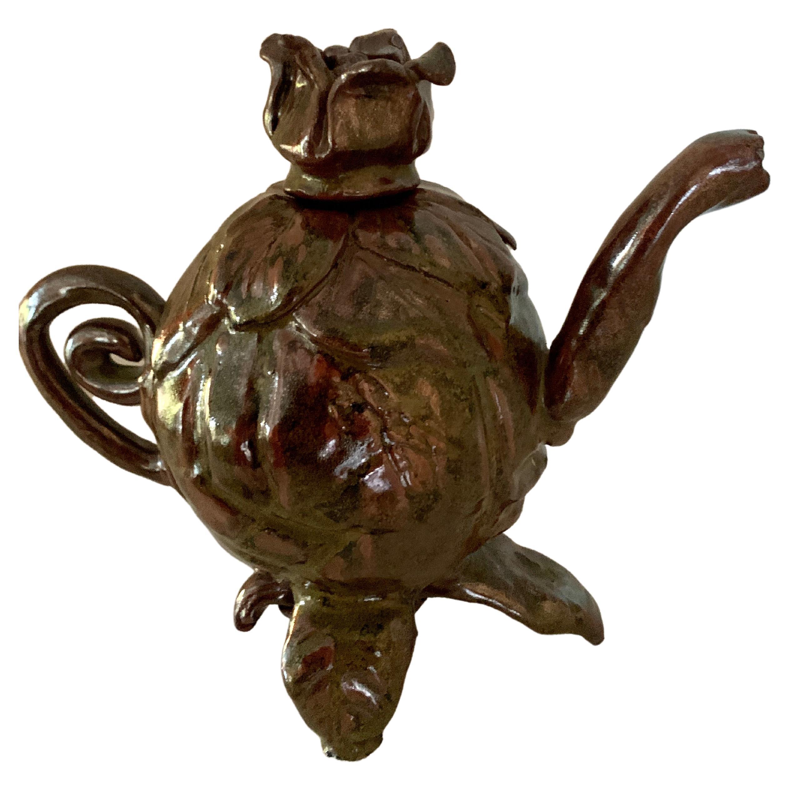 A Folk Art Studio pottery teapot - a uniquely hand crafted tea pot with a whimsical style and compliment to any kitchen or shelf for art. The pot has a removable stem and has an array of fascinating colors in the glaze.