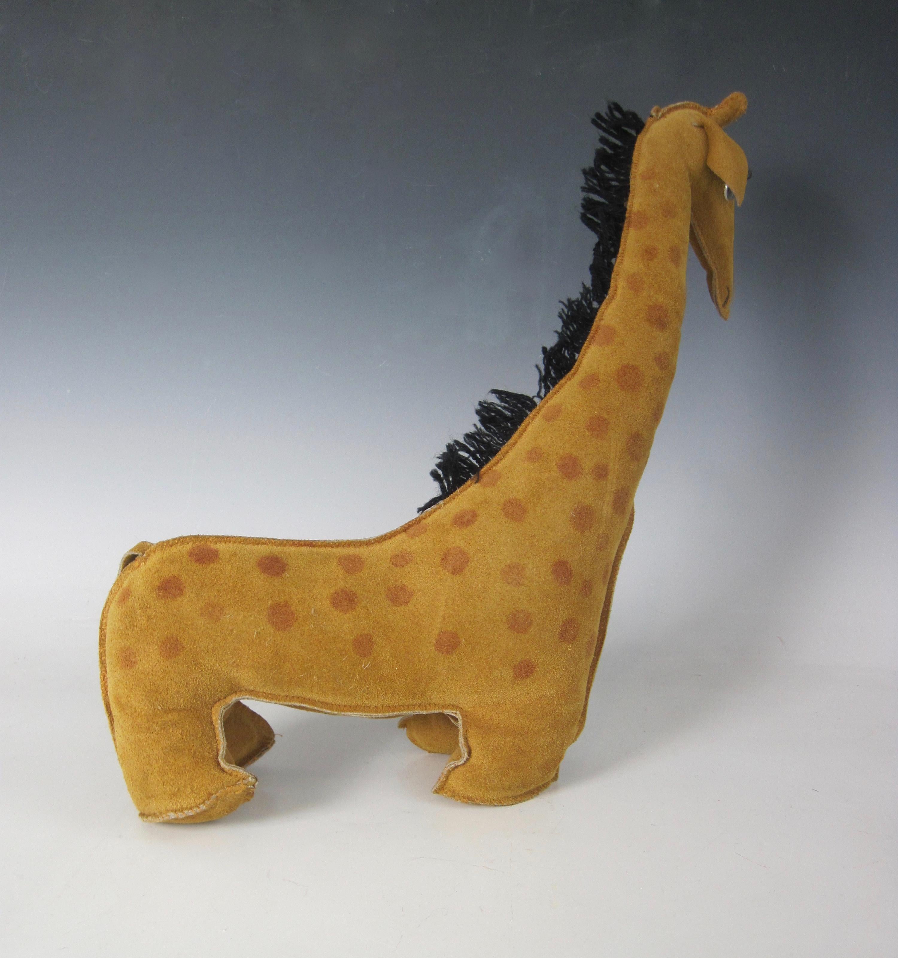 Vintage 1970s tan suede leather spotted Giraffe stuffed animal complete with sewn-on plastic eyes and lashes and a mane made of black yarn. All seaming is tight. No stains.