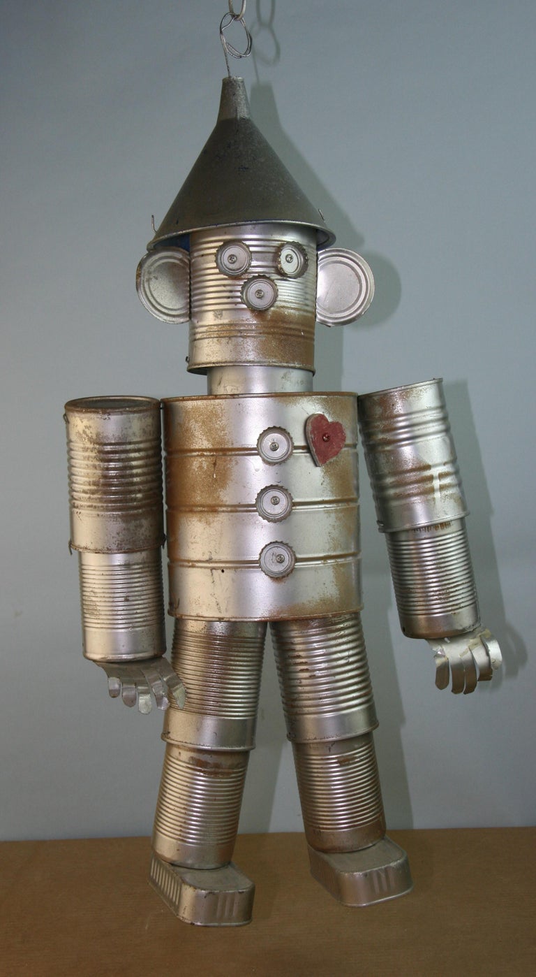 A Folk Art sculptural figure made from tin cans, bottle tops and plastic funnel 
It has moveable joints due to the cans being connected with wire and screws.
Supplied with 2 feet of chain. Can be used as a wind chime.