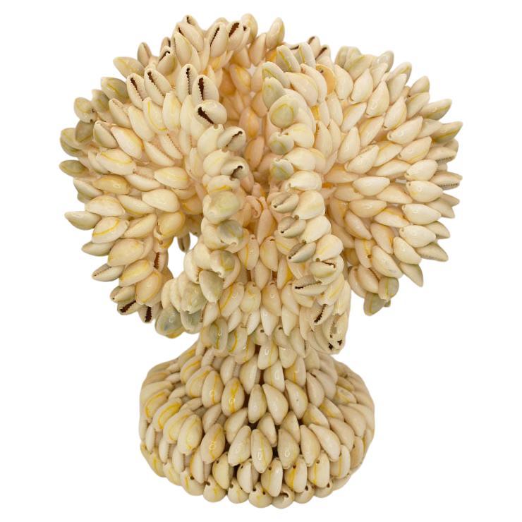 A unique vase created from seashells. Strung together, the rim of the vase is formed to resemble a ruffled look. The body of the base is round, with a wider bottom. Set a clear glass vase inside this beauty to hold flowers with water. Or, use it to