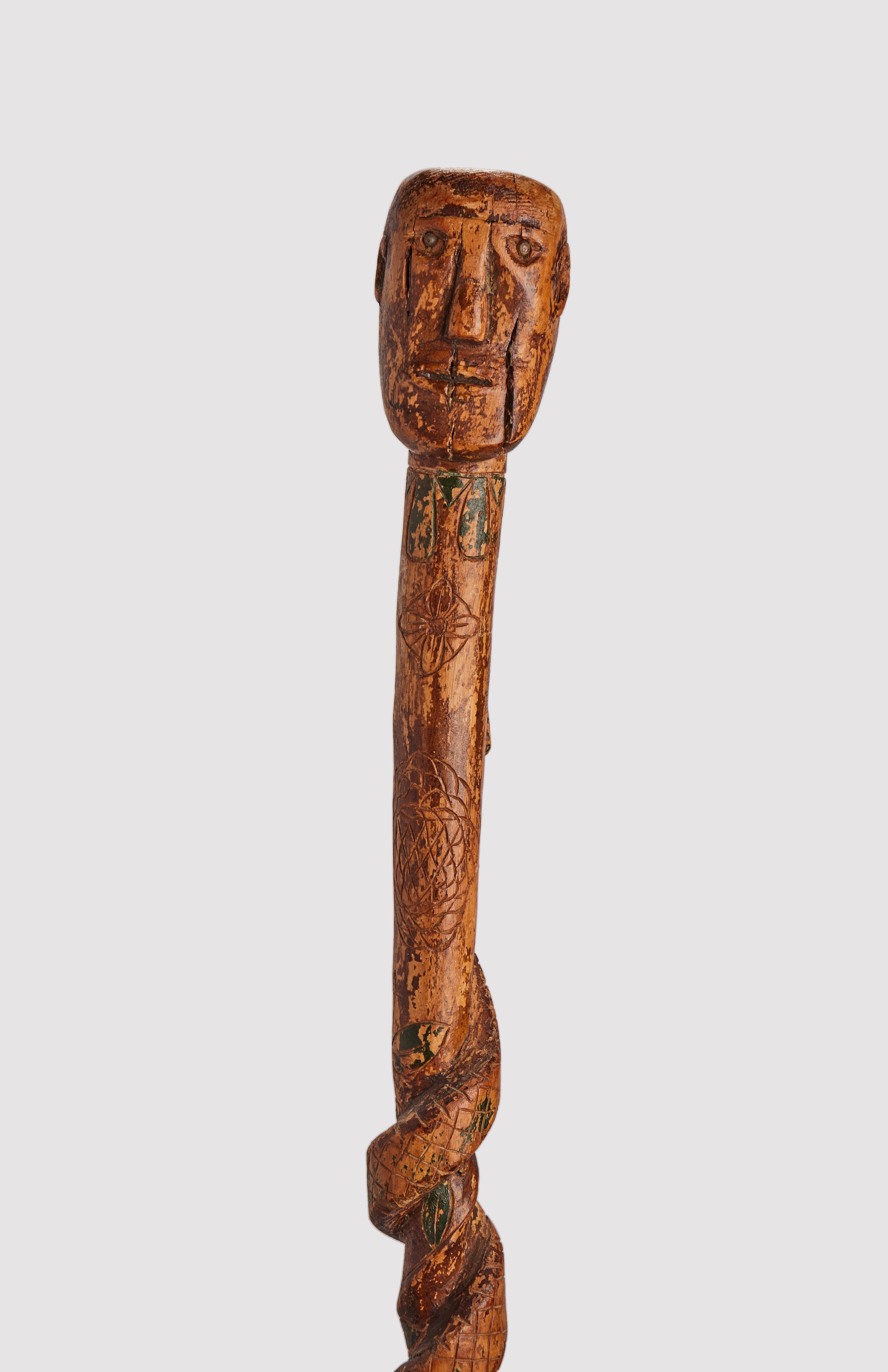 Folk art walking stick: one piece of fruitwood depicting the head of a man with snake along the curved shafts painted green. End of 19th century.