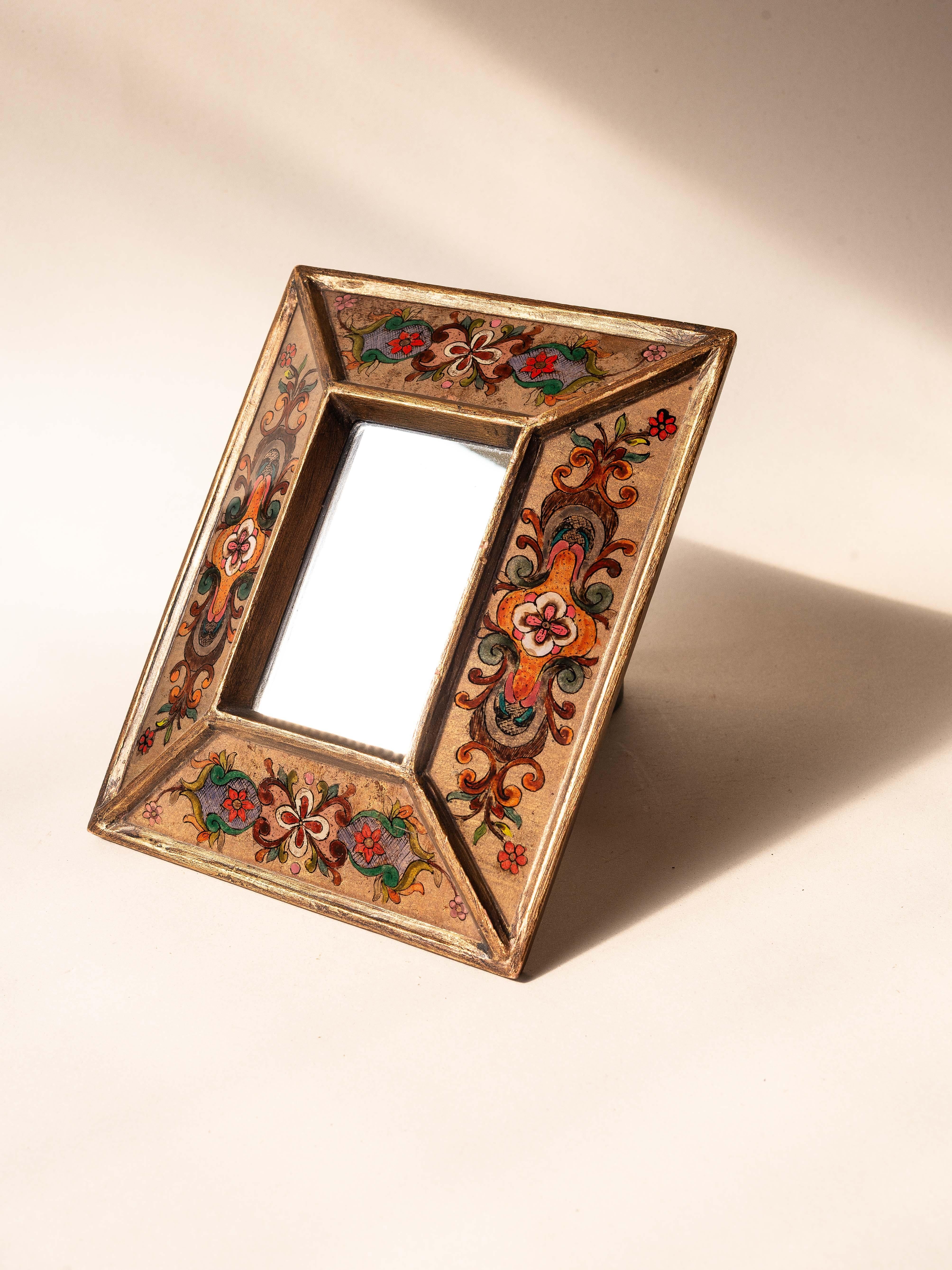 Miroir mural d'artisanat, motifs floraux peints à la main et cadre doré, Pérou 1970

Ajoutez une touche de charme folklorique vibrant à votre espace avec ce miroir péruvien des années 1970. 

Le cadre en bois comporte quatre panneaux inclinés,
