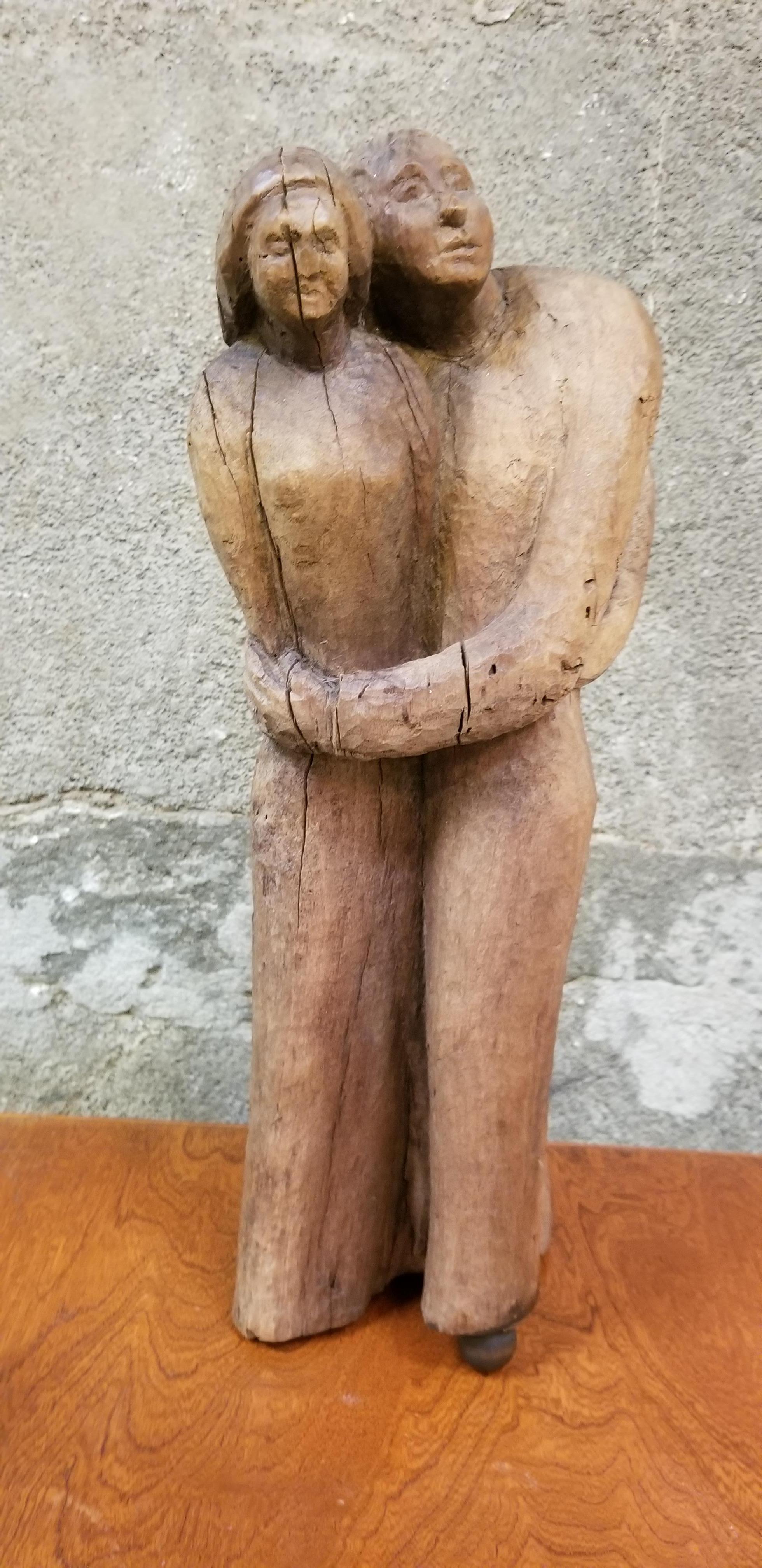 A hand carved wood sculpture of 3 standing and embracing figures. Unknown artist or age. Appears to be from the 1930s. Skilful whittled effect with strong expression to male and female figures. Measures 19.5 inches in height.