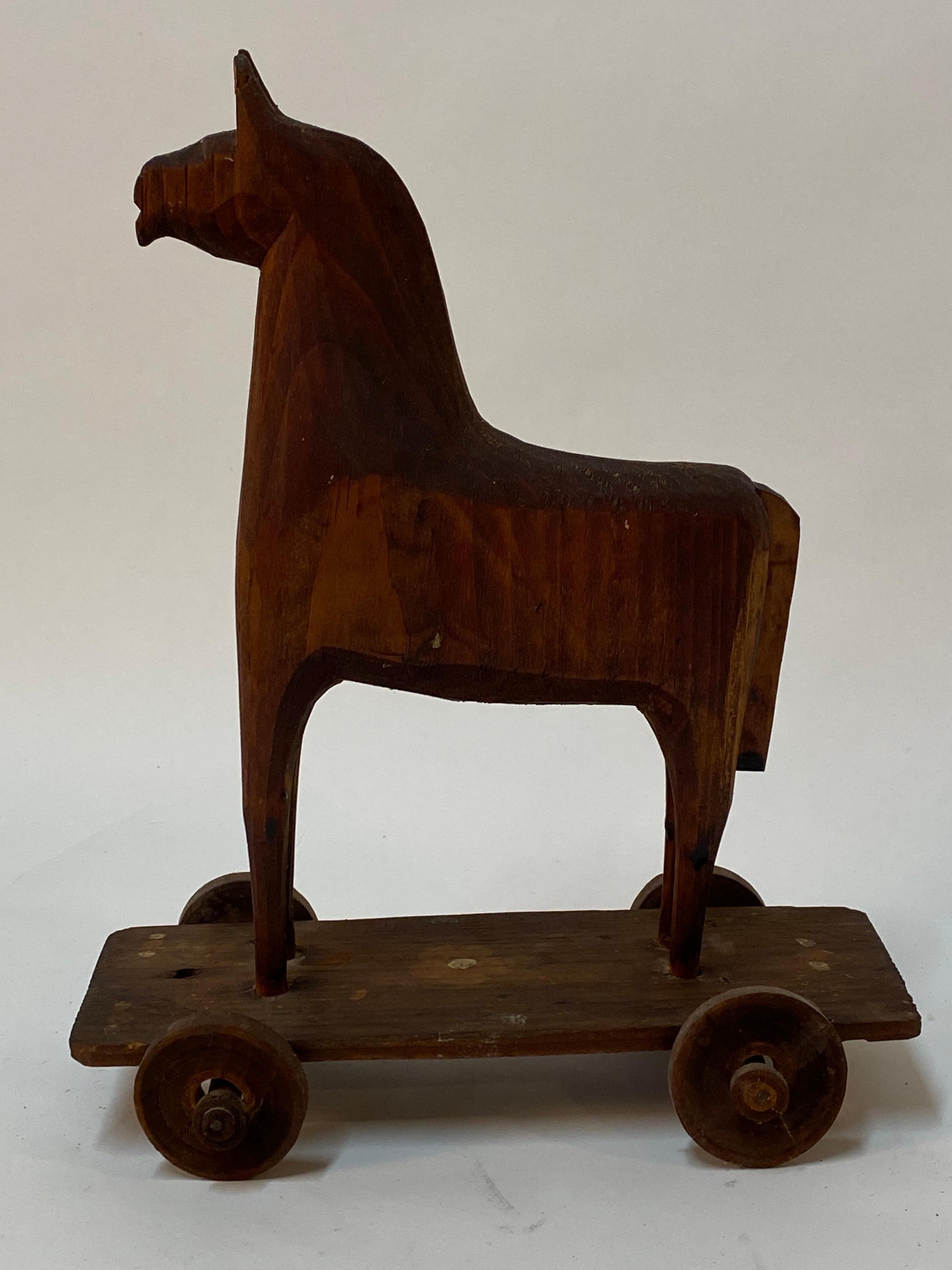 Fantastic hand crafted carved wood horse pull toy. Possibly made from scraps of wood during the Depression Era resembling a Trojan Horse of sorts. Carved pine. There are few nails used in the construction where the tail and the wheels are applied to