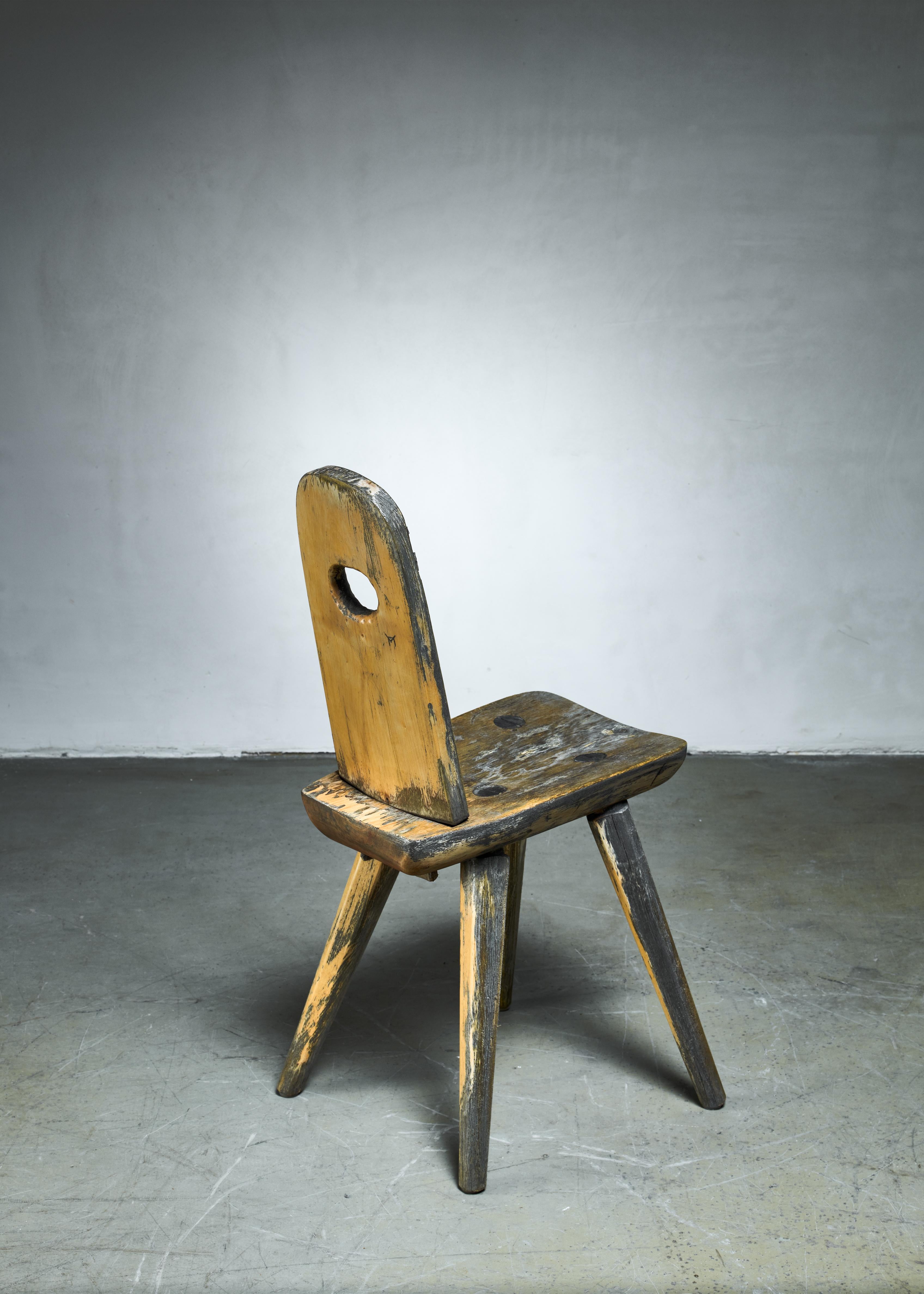 An early 20th century folk art side chair from Sweden, made of partly lacquered wood.

The backrest is fixed with two wooden pins underneath.