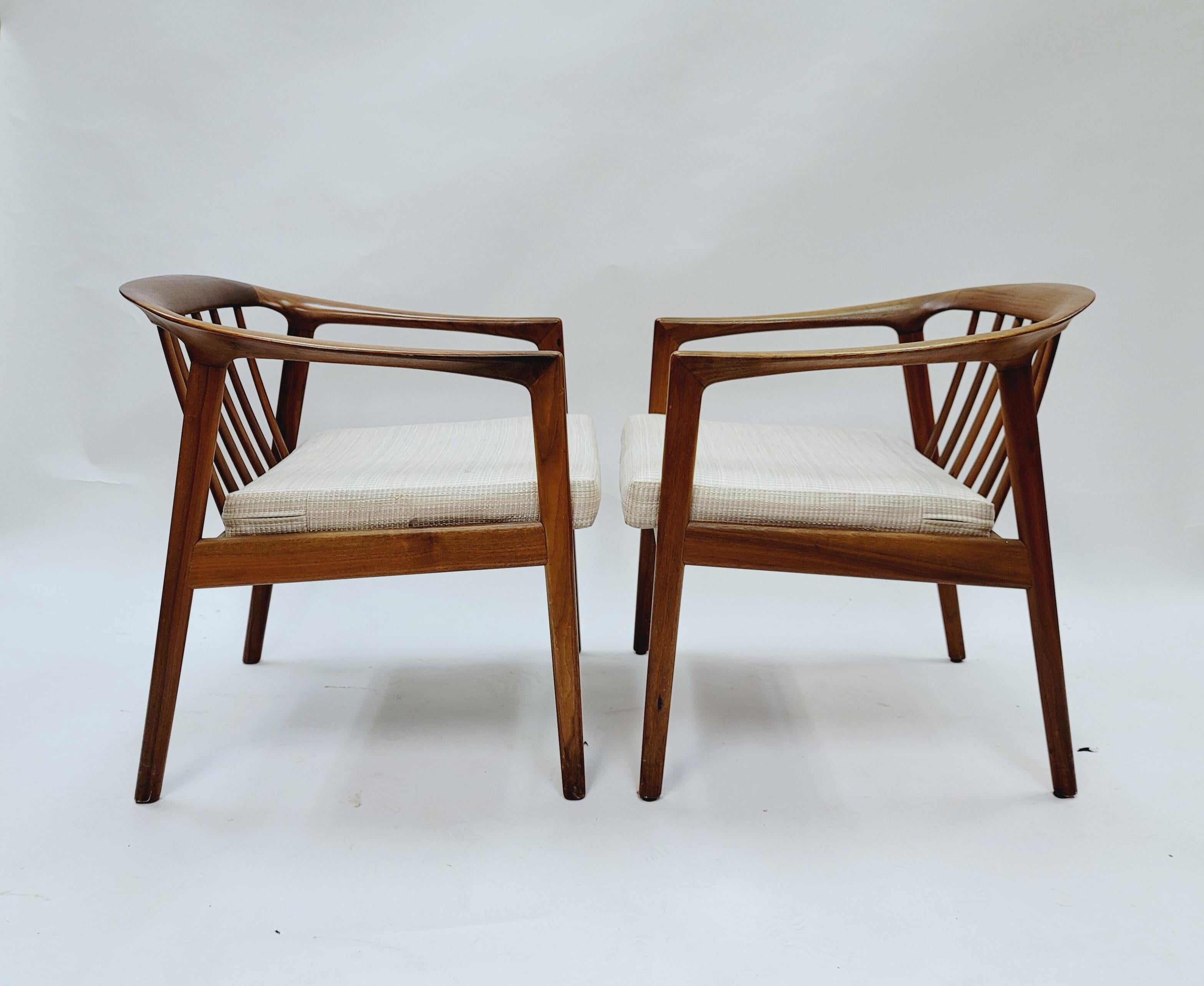 Pair of upholstered armchairs in teak designed by Folke Ohlsson and manufactured by Dux. Crafted from teak, the sculptural curve of the chair is highlighted by the elegant joinery. Stamped with the makers logo on the underside.