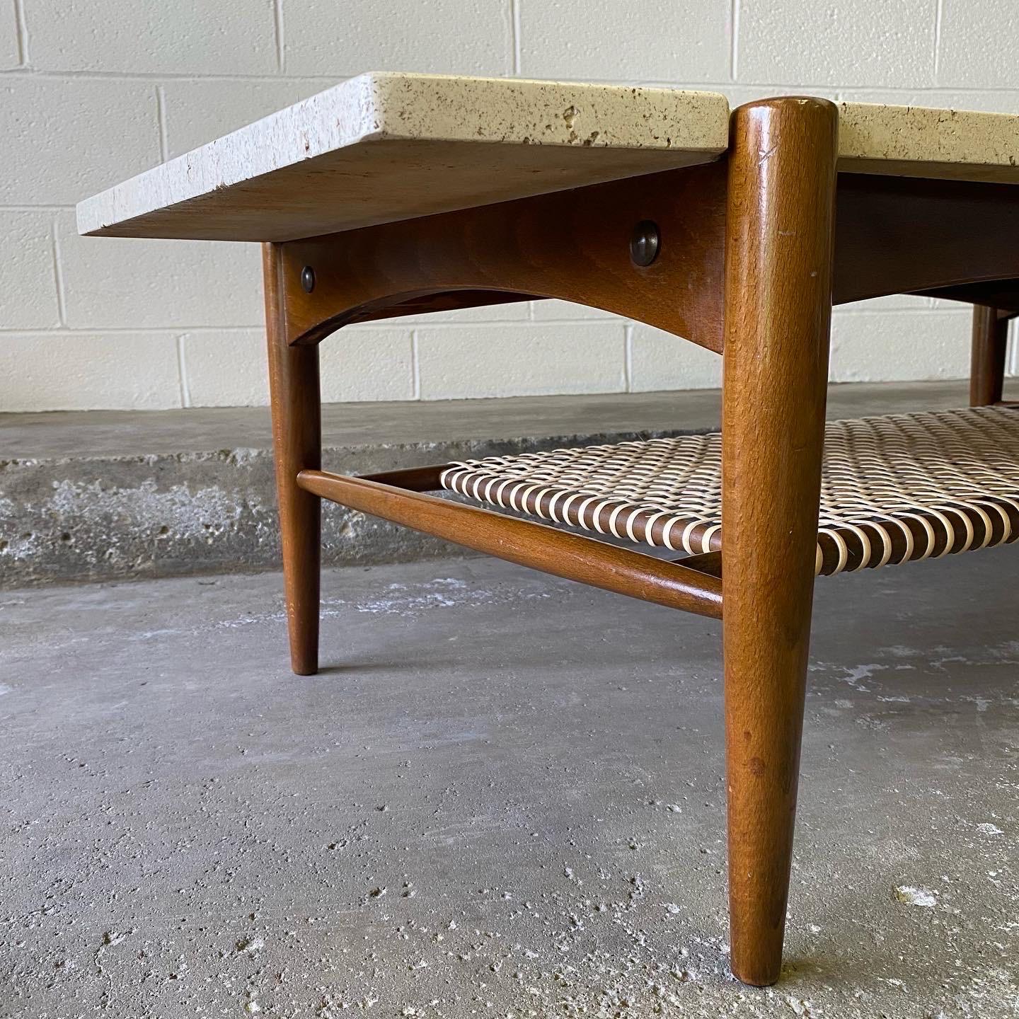 This is an excellent Danish modern coffee table designed by Folke Ohlsson for Dux of Sweden in the 1960’s. It features beautiful sculpted walnut with a solid travertine top, new, professionally installed cane, and brass detail. It’s subtle yet