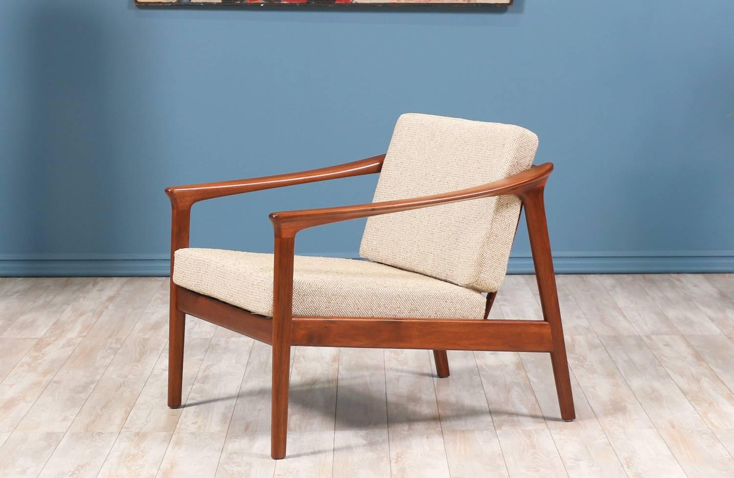 Model 1073-C Lounge Chair designed by Folke Ohlsson for Dux of Sweden circa 1950’s. Newly refinished Scandinavian modern design, featuring a walnut wood frame with eight slats on the open back and curvilinear arm rests. The cushions are