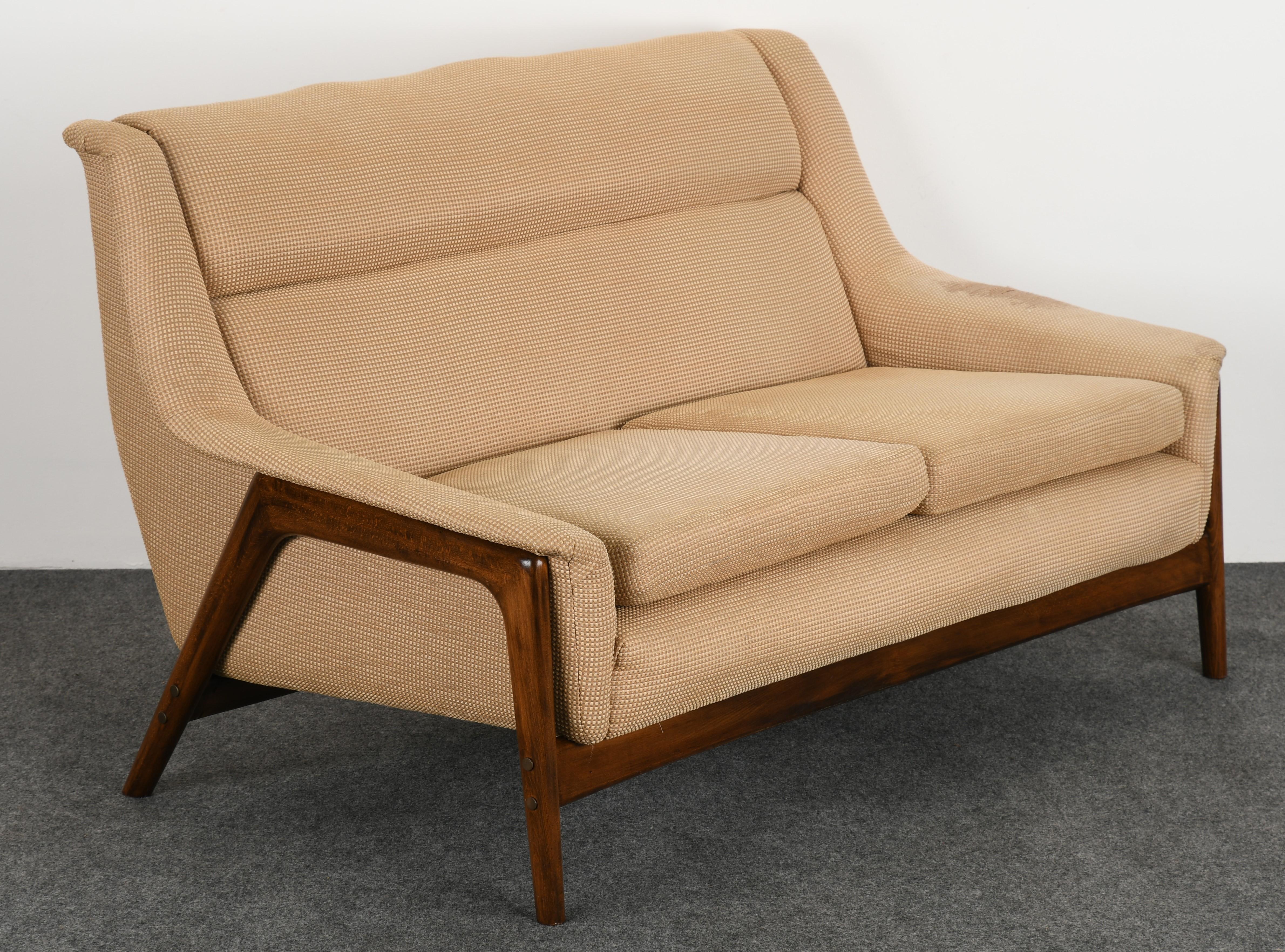 A modernist settee designed by Folke Ohlsson for DUX. The settee has a sleek modern beech wood sculptural frame. This is a great example of Mid-Century Modern. The settee is structurally sound, however, some spots to the fabric. New upholstery is